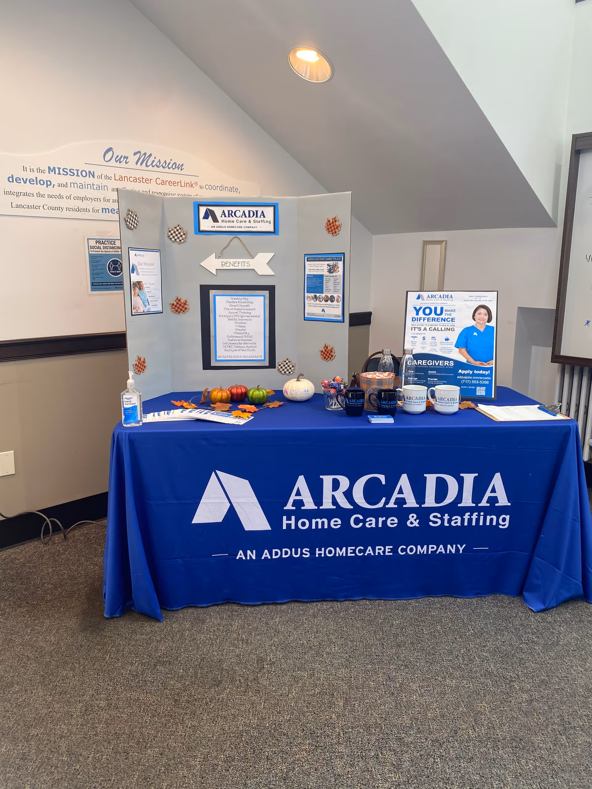 Indoor booth for Arcadia Home Care & Staffing with brochures and a blue table.