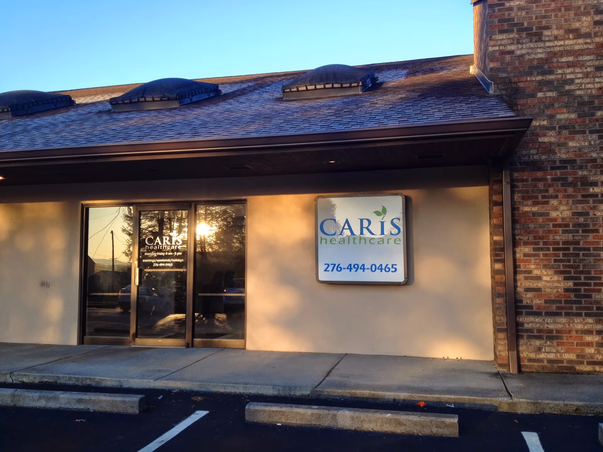 Exterior view of Caris Healthcare facility entrance with sign and parking lot.