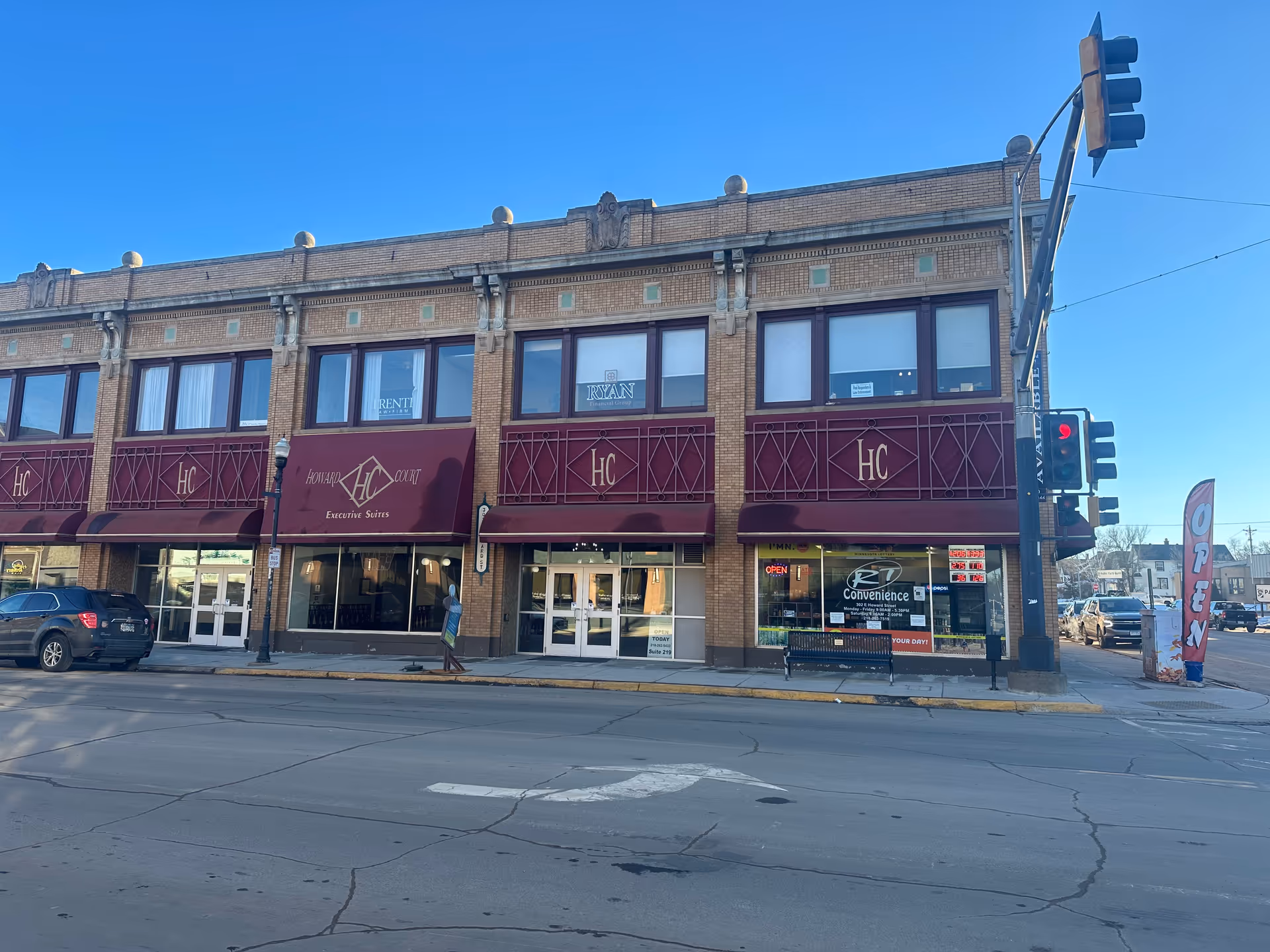 Two-story brick building with maroon awnings along a city street