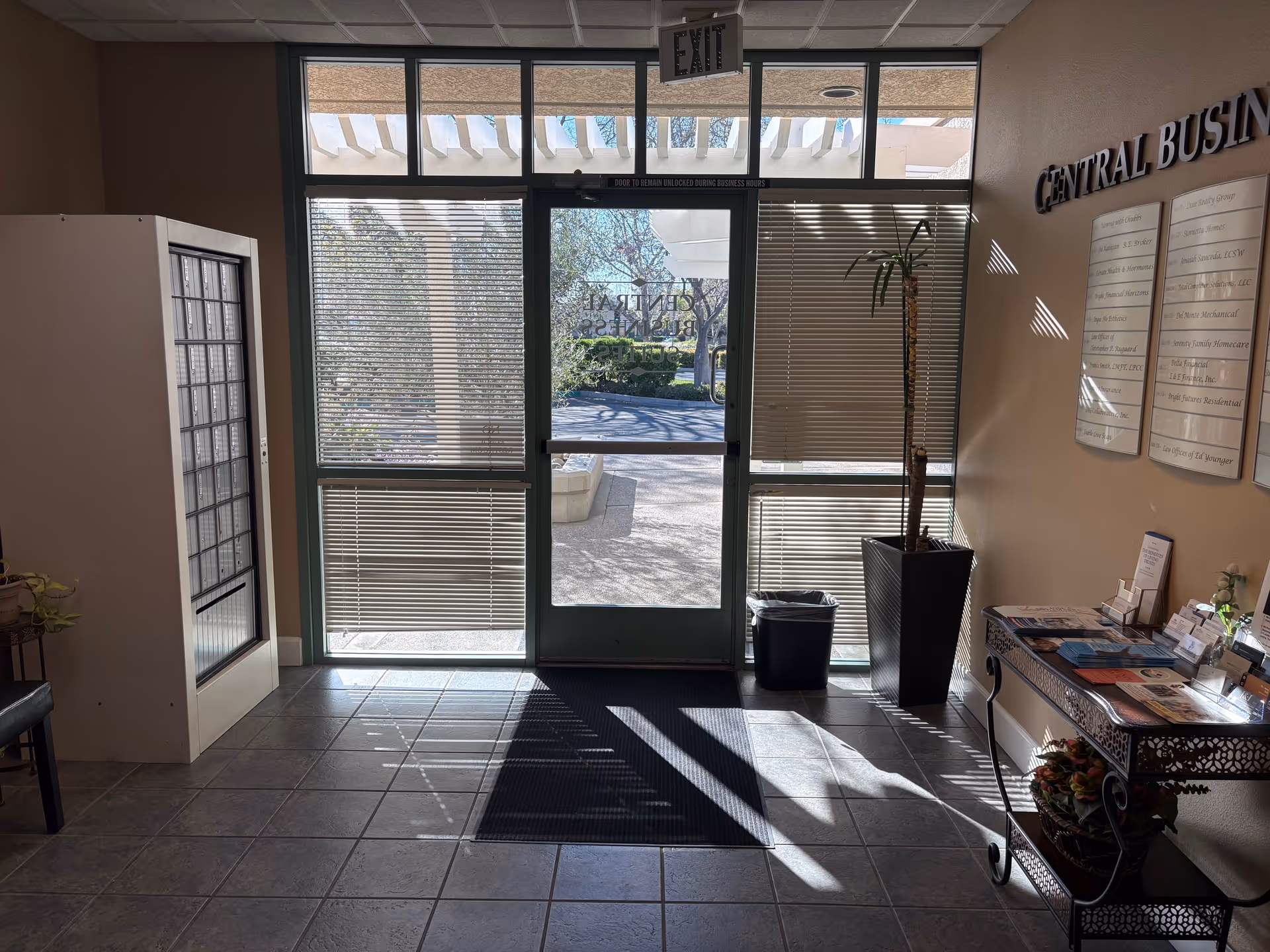 Interior lobby of a senior facility with glass doors, blinds, and a brochure table.