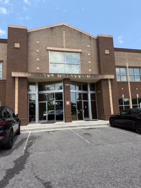 Brick building entrance with glass doors and 'THE MILLENNIUM' sign.