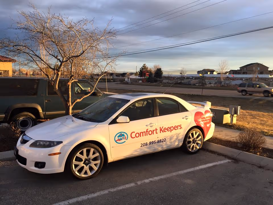White Comfort Keepers car with logo parked in a lot outside a neighborhood