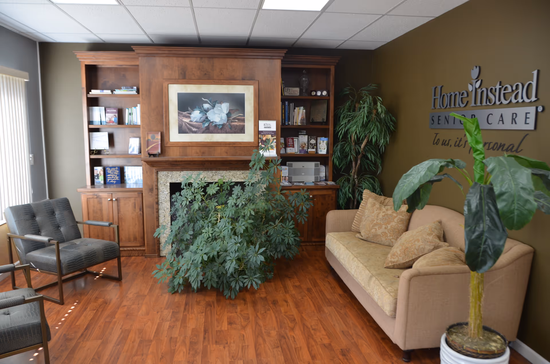 Wood-paneled reception area with sofa, chairs, plants, and a Home Instead sign on the wall.