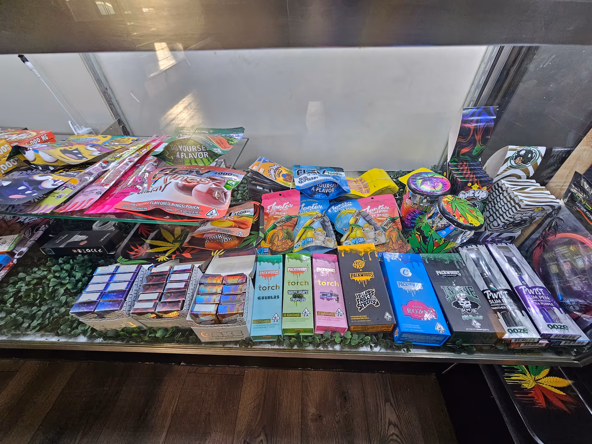 Glass display case filled with colorful cannabis products and packaging.