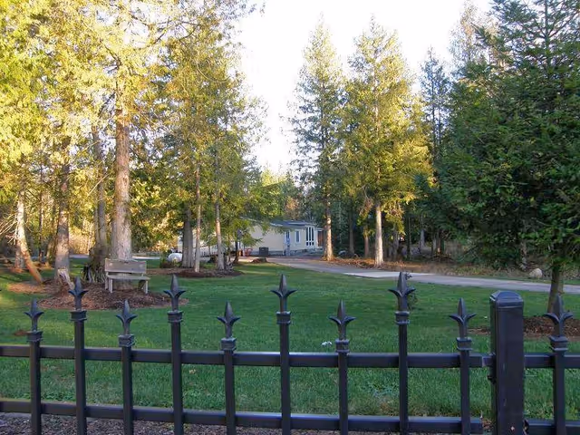 Outdoor view of Taylor Adult Family Home's fenced yard with trees and benches.
