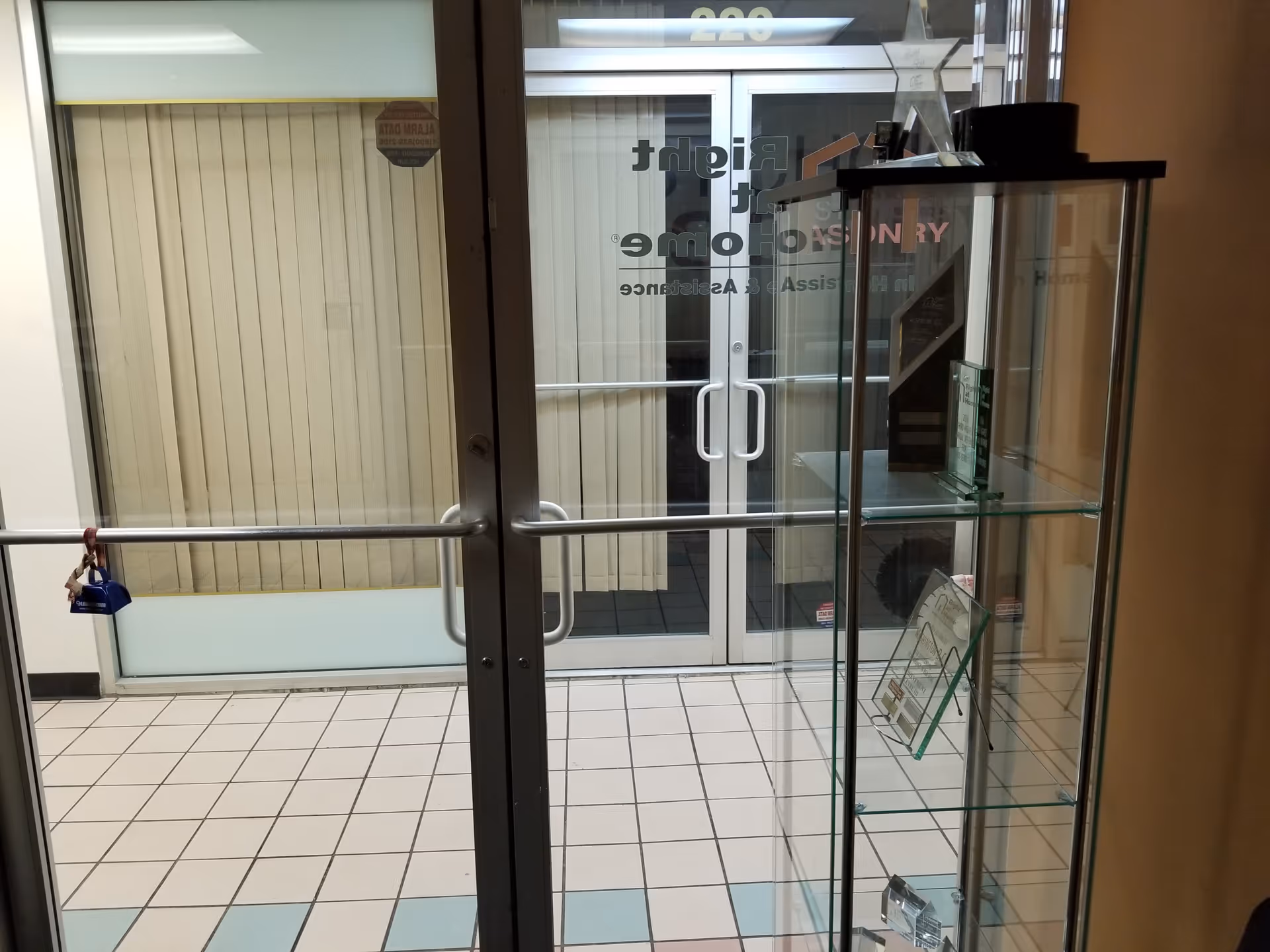 Interior view of Right at Home lobby with glass doors and a display cabinet.