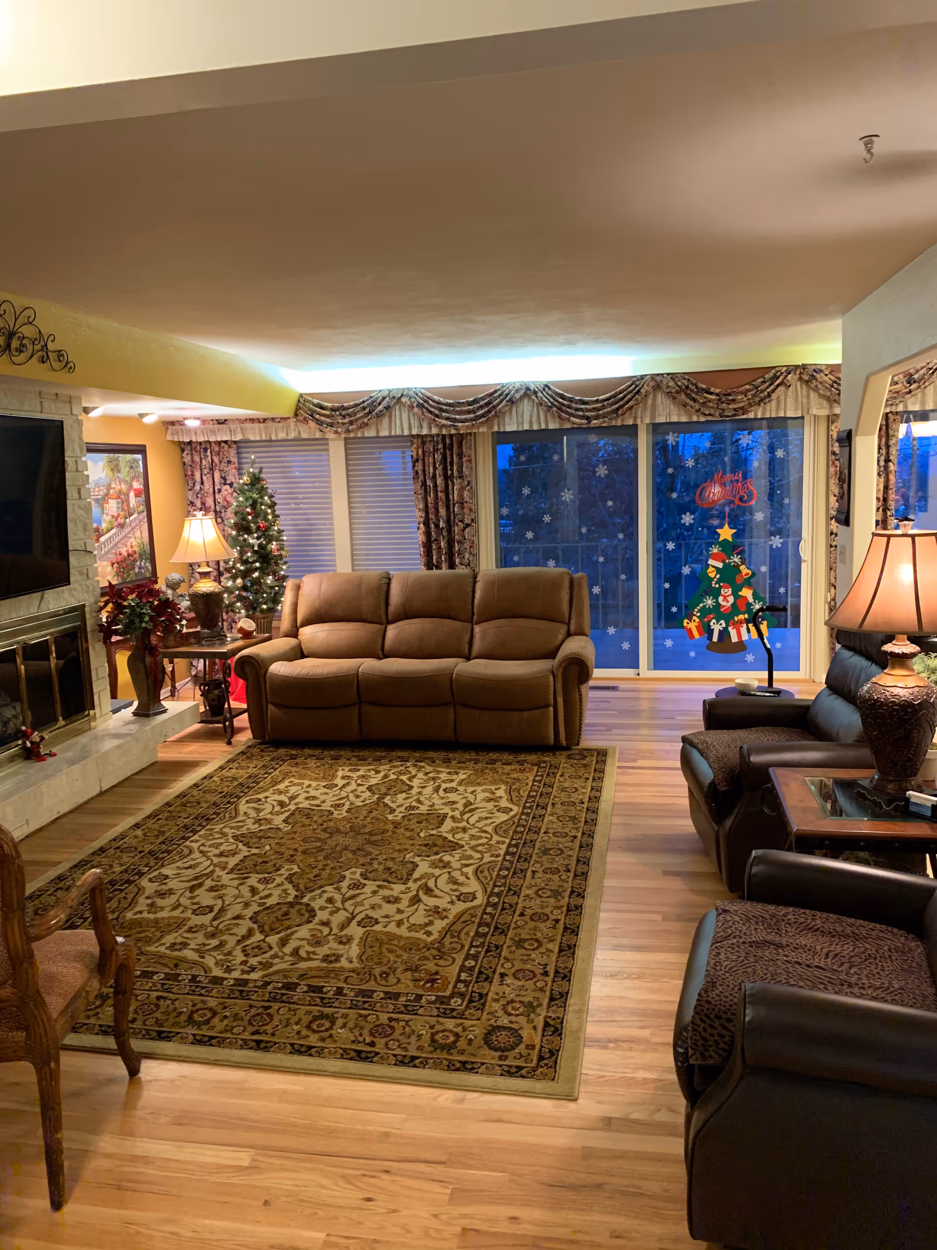 Cozy living room with leather sofa, recliners, lamps, and festive winter decor.