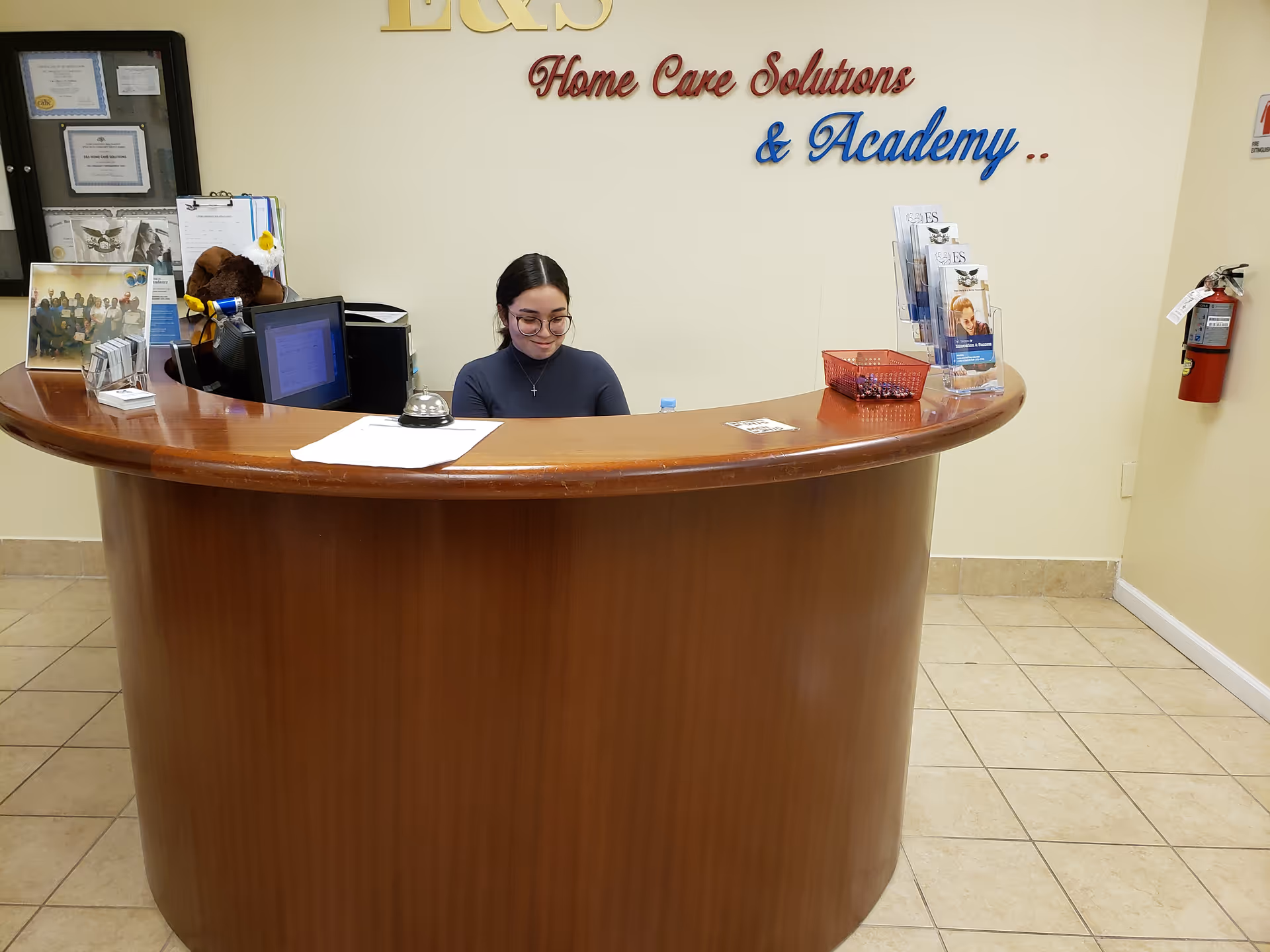 Reception desk with a staff member in a lobby, signage reads Home Care Solutions & Academy.