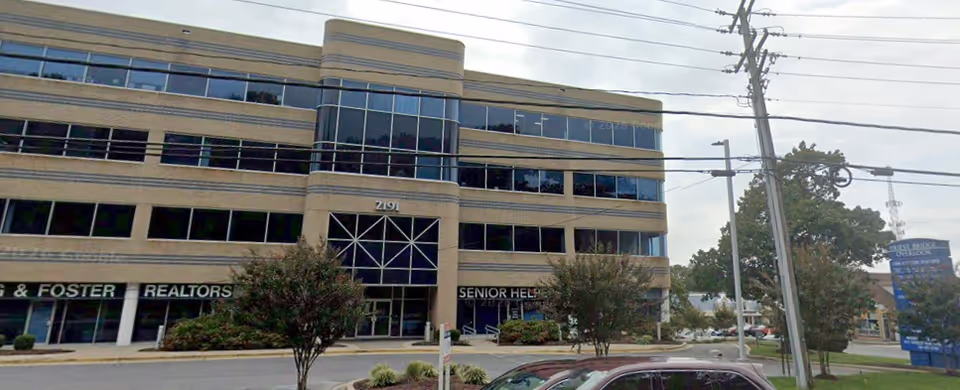 Multi-story Senior Helpers building with glass entrance on a street corner.