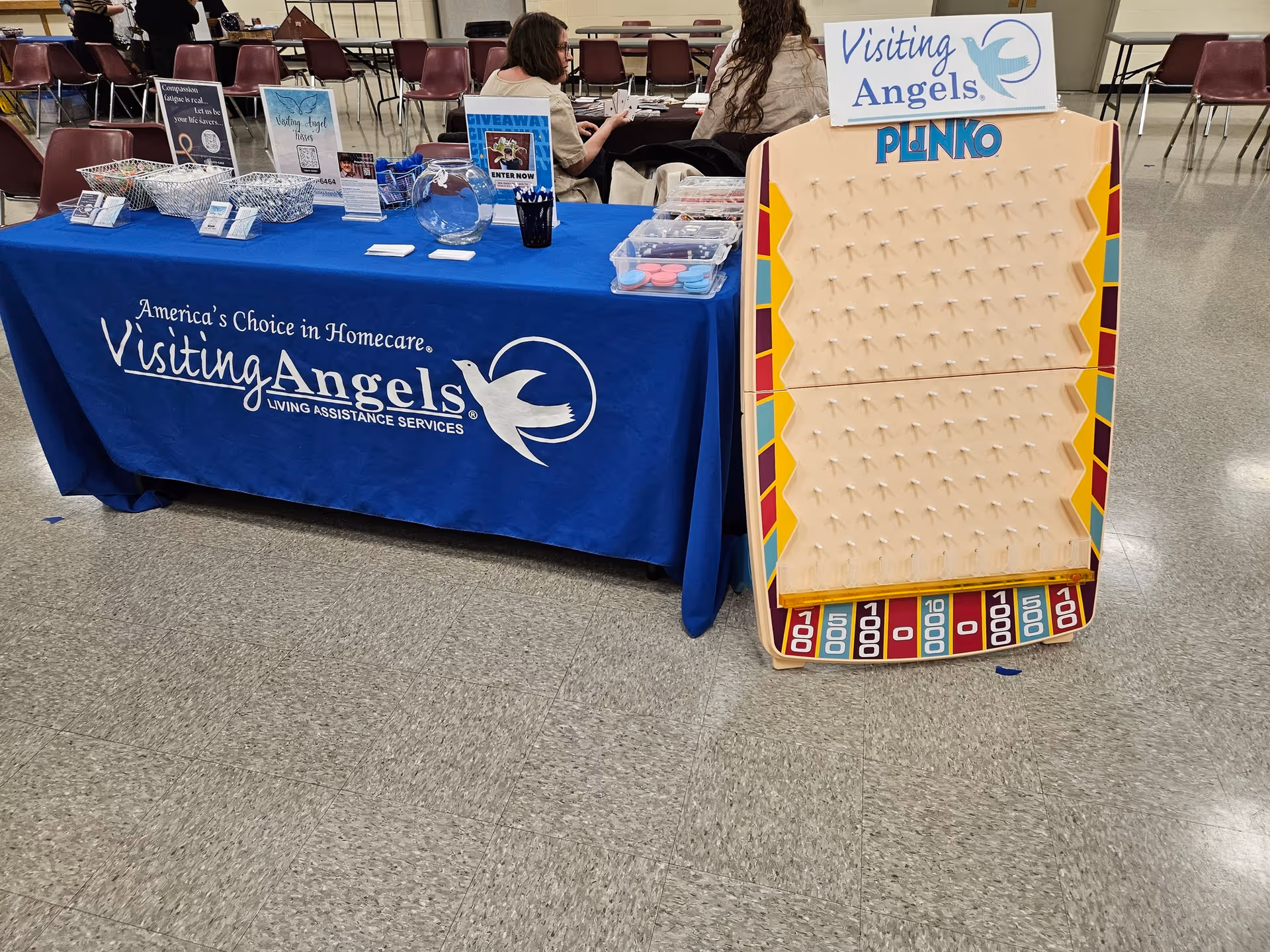 Promotional booth for Visiting Angels in Plainwell with blue tablecloth and Plinko board inside.