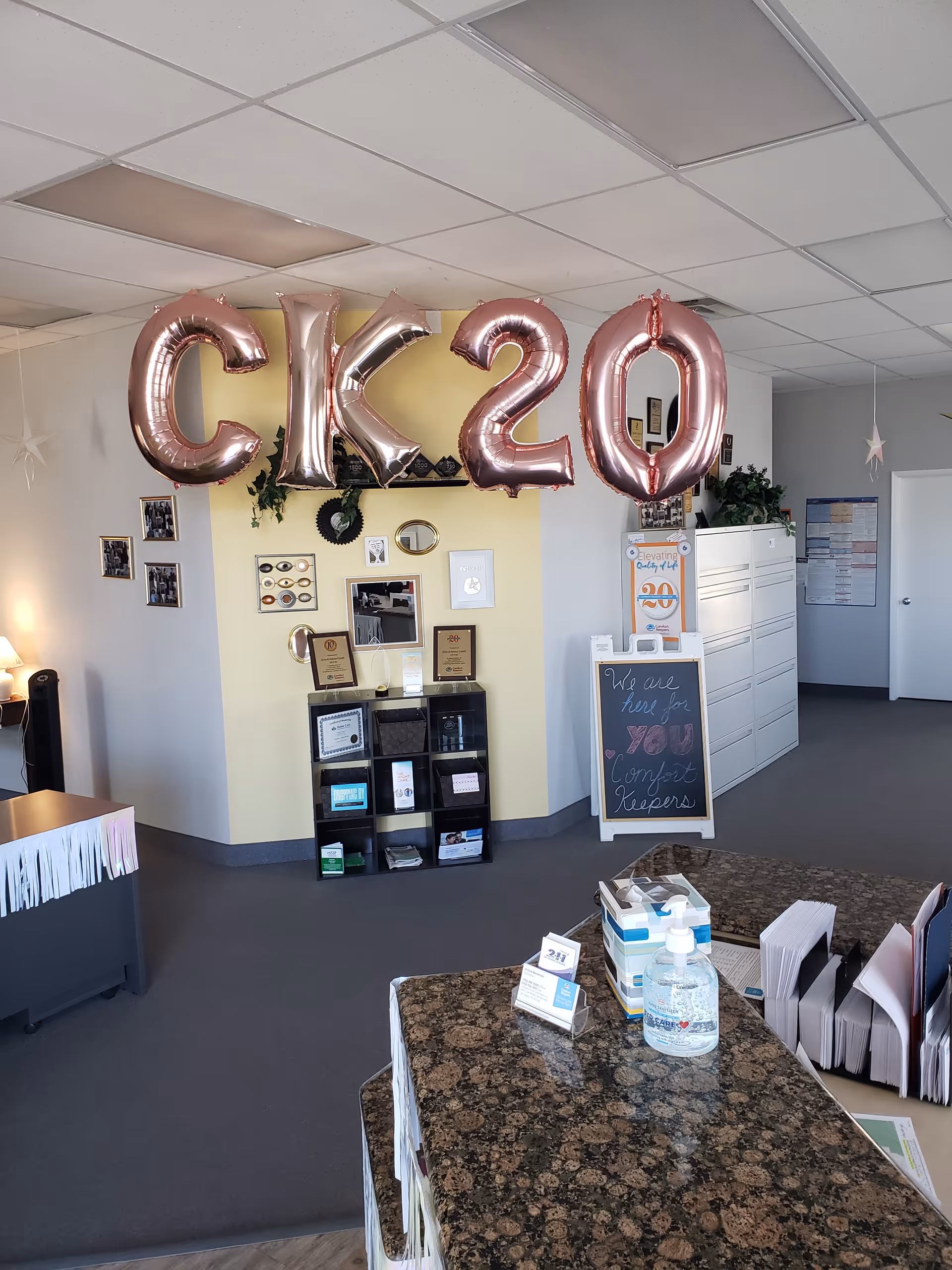 Indoor reception area with pink CK20 balloons and a chalkboard sign