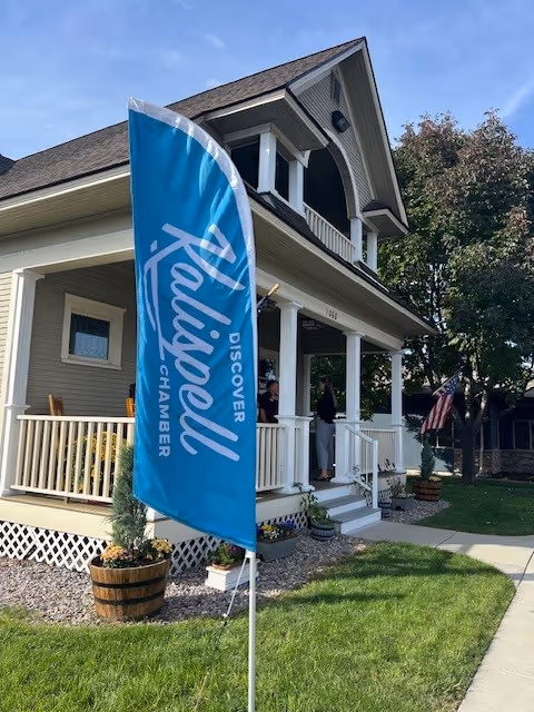 Exterior view of a Home Instead facility with a blue flag and people on the porch.