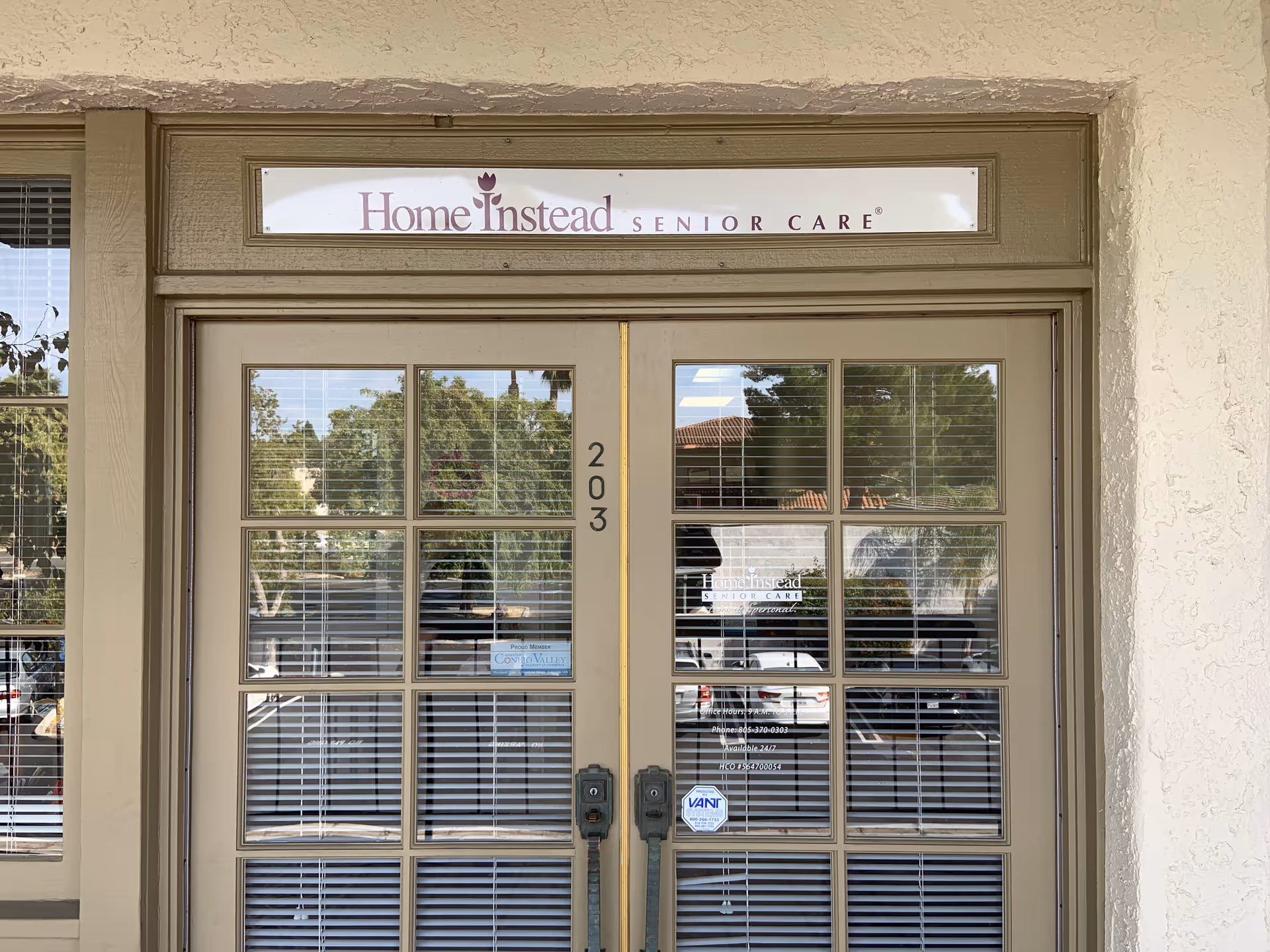 Beige building entrance with glass double doors and a Home Instead Senior Care sign above.