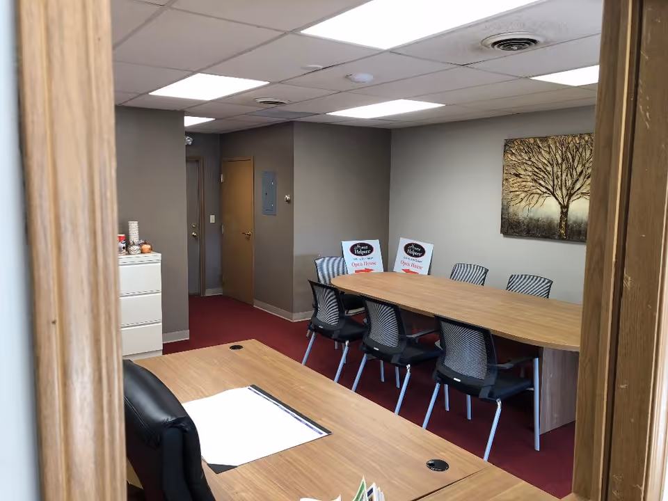 An empty conference room with a long table, chairs, and wall art.