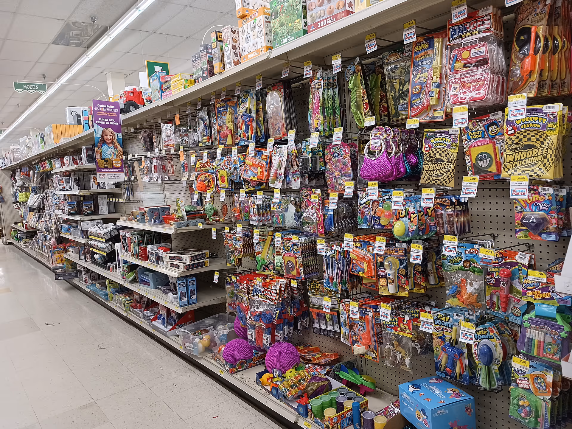 Aisle of toys and novelty items on pegboard shelves in a store.