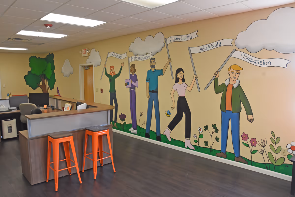 Interior common area with a curved reception desk, orange stools, and mural wall art.