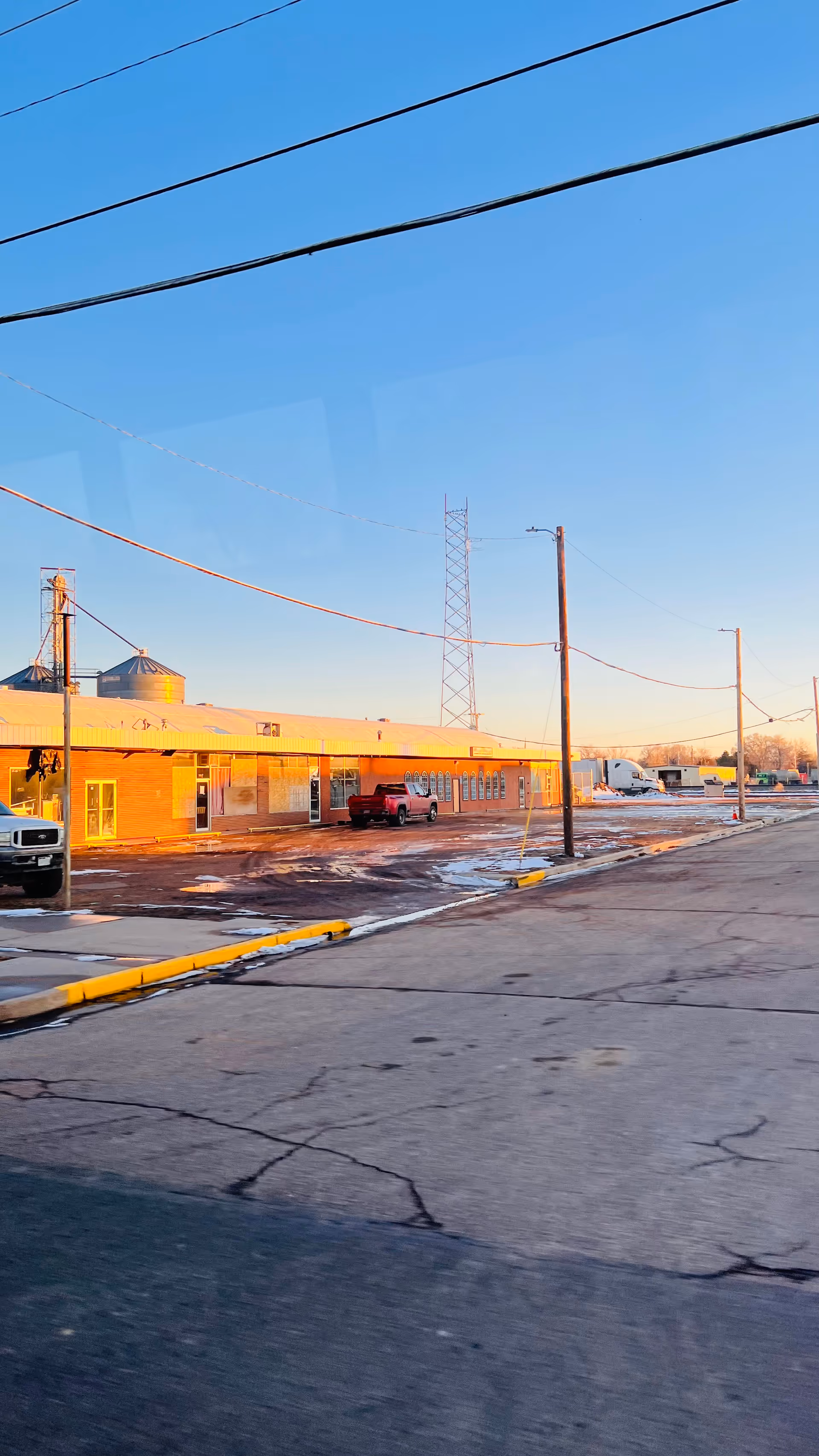 Exterior view of a single-story brick facility with parking and power lines.