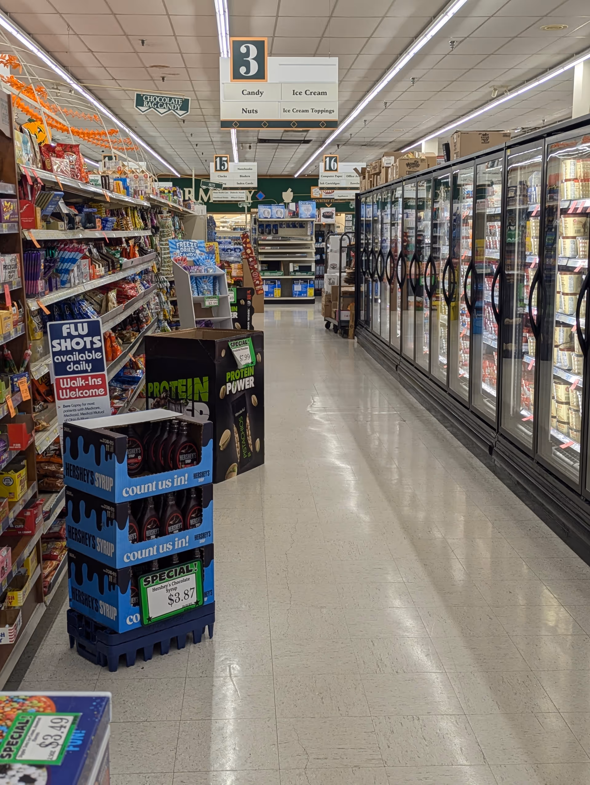 A grocery-style aisle inside Discount Drug Mart with shelves and coolers.