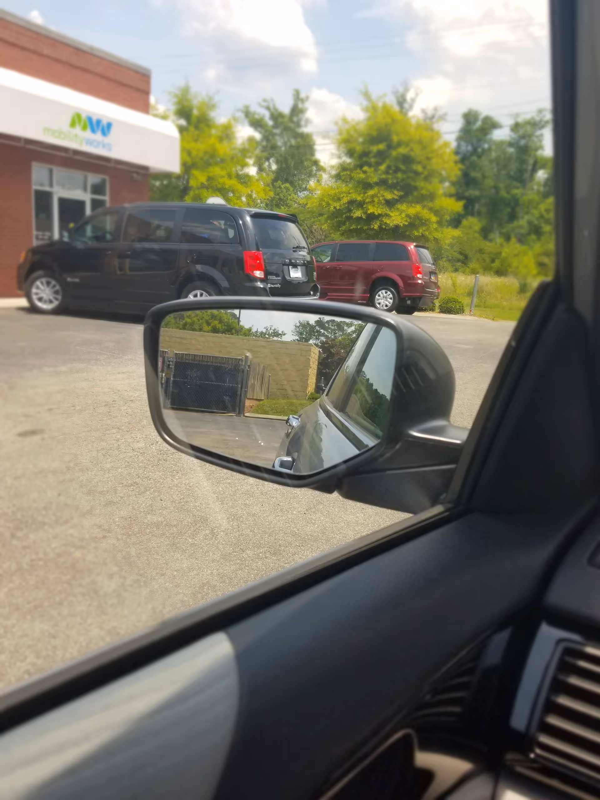 View from inside a car of MobilityWorks building and parked vehicles at the front.