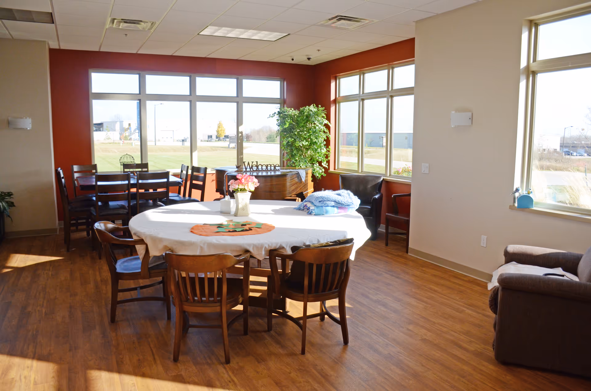Bright common dining and lounge area with a round table and large windows.