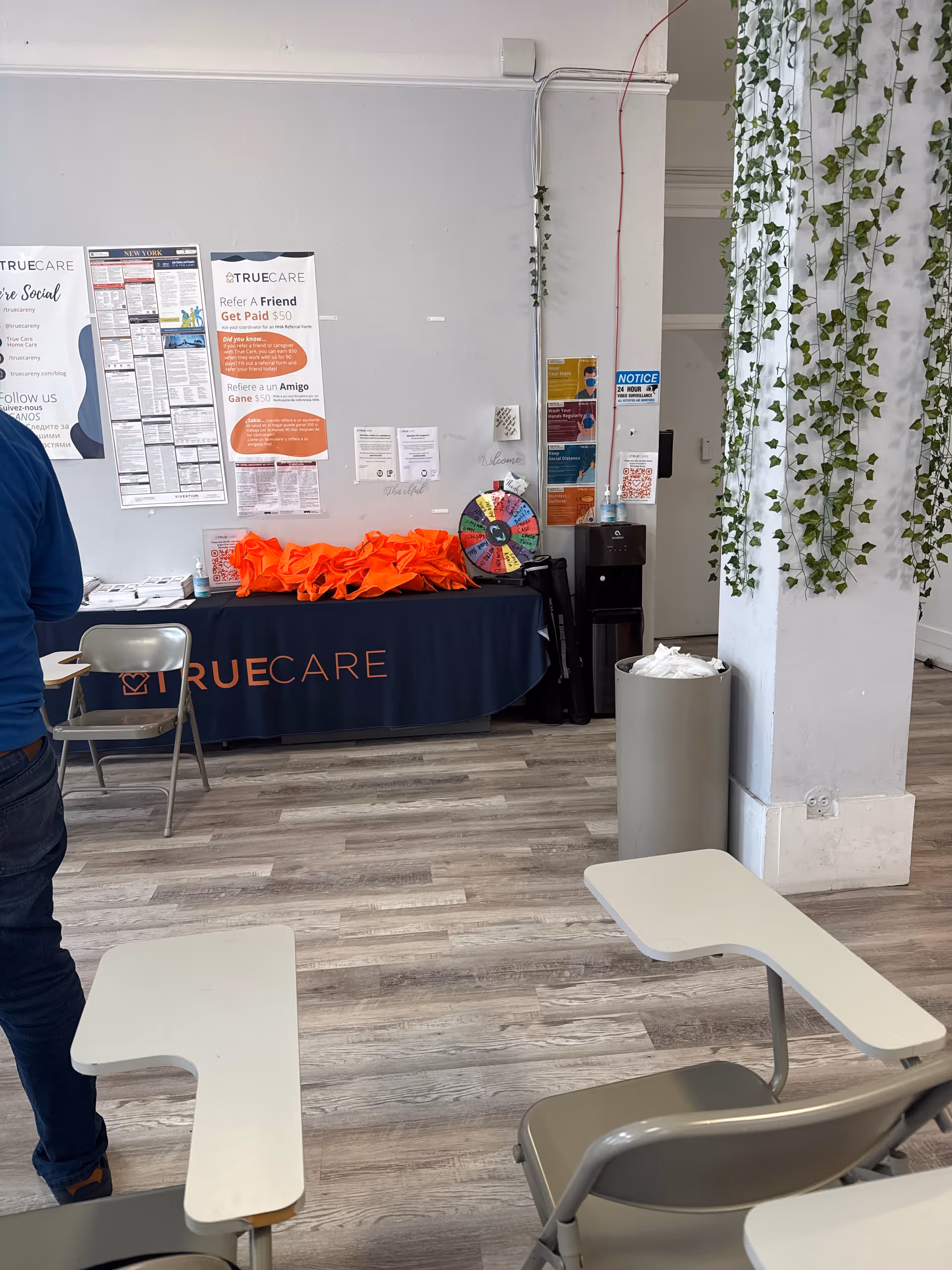 Indoor reception area featuring a TrueCare table, posters, and a colorful prize wheel