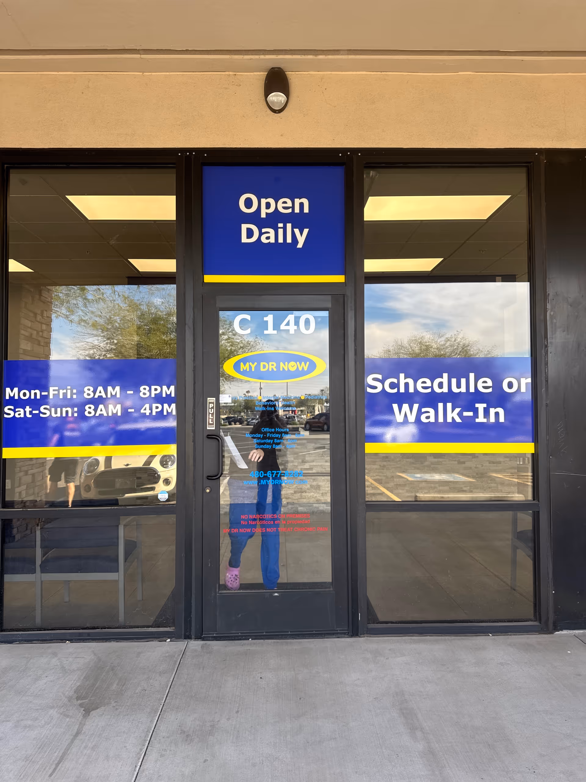 Exterior storefront entrance for My Dr Now with an Open Daily sign and blue window decals.
