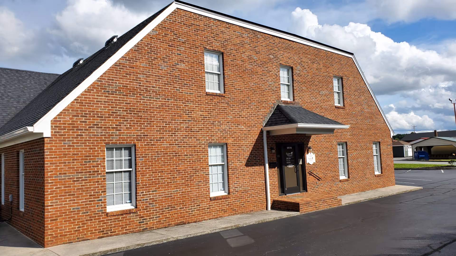 Red brick facility exterior with multiple windows and a front entrance.