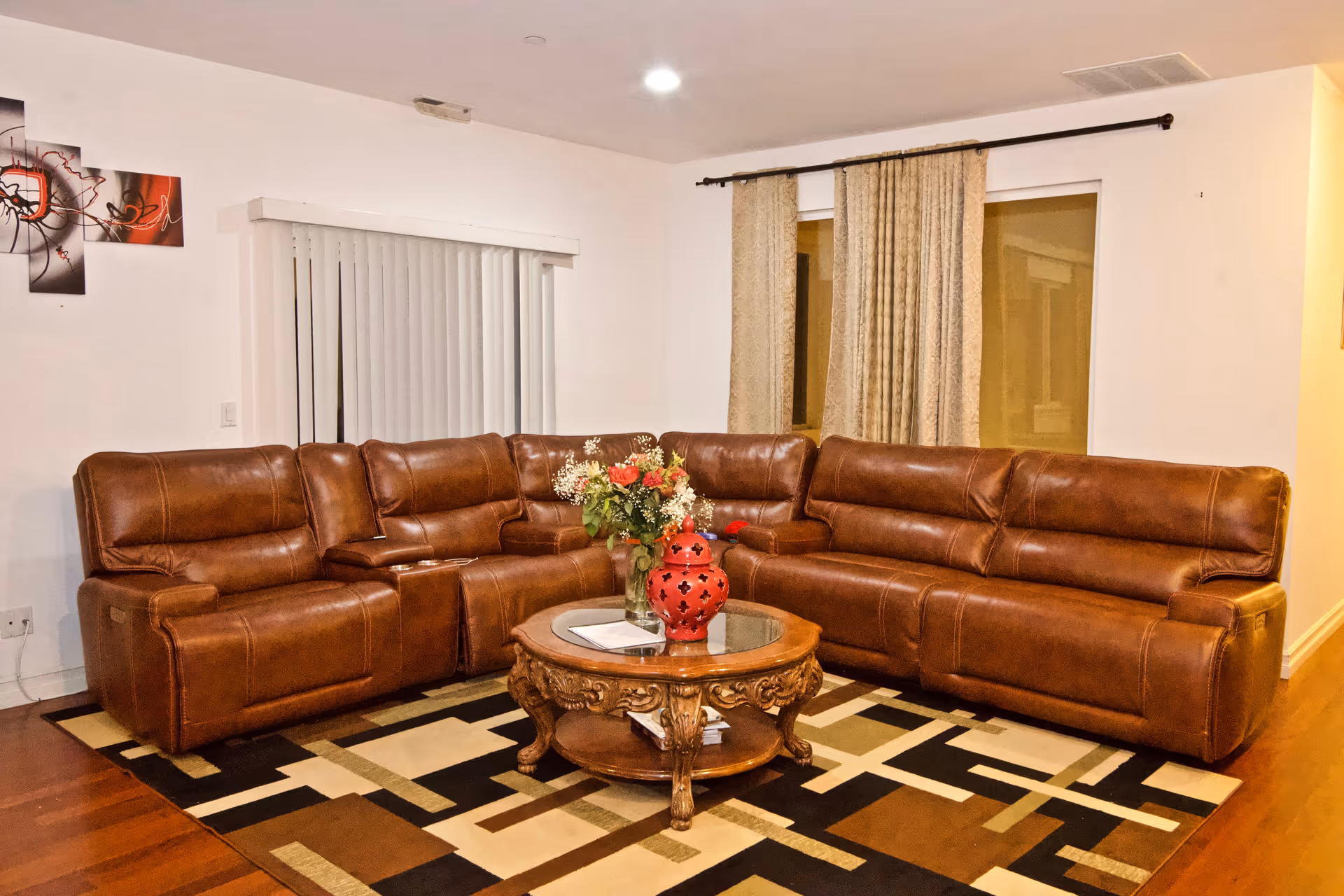 Brown leather sectional sofa surrounds a glass coffee table in a cozy living room.