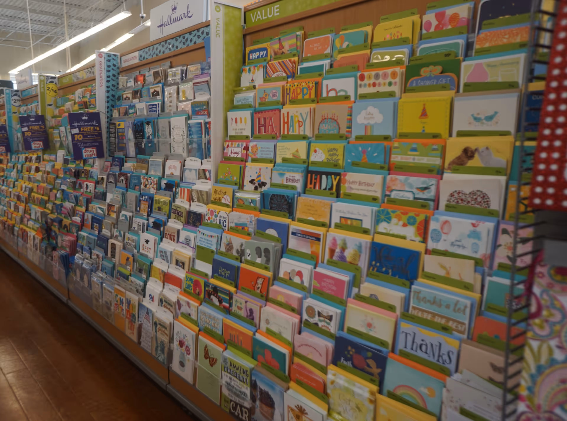 A long wall of colorful greeting cards displayed in a store aisle.