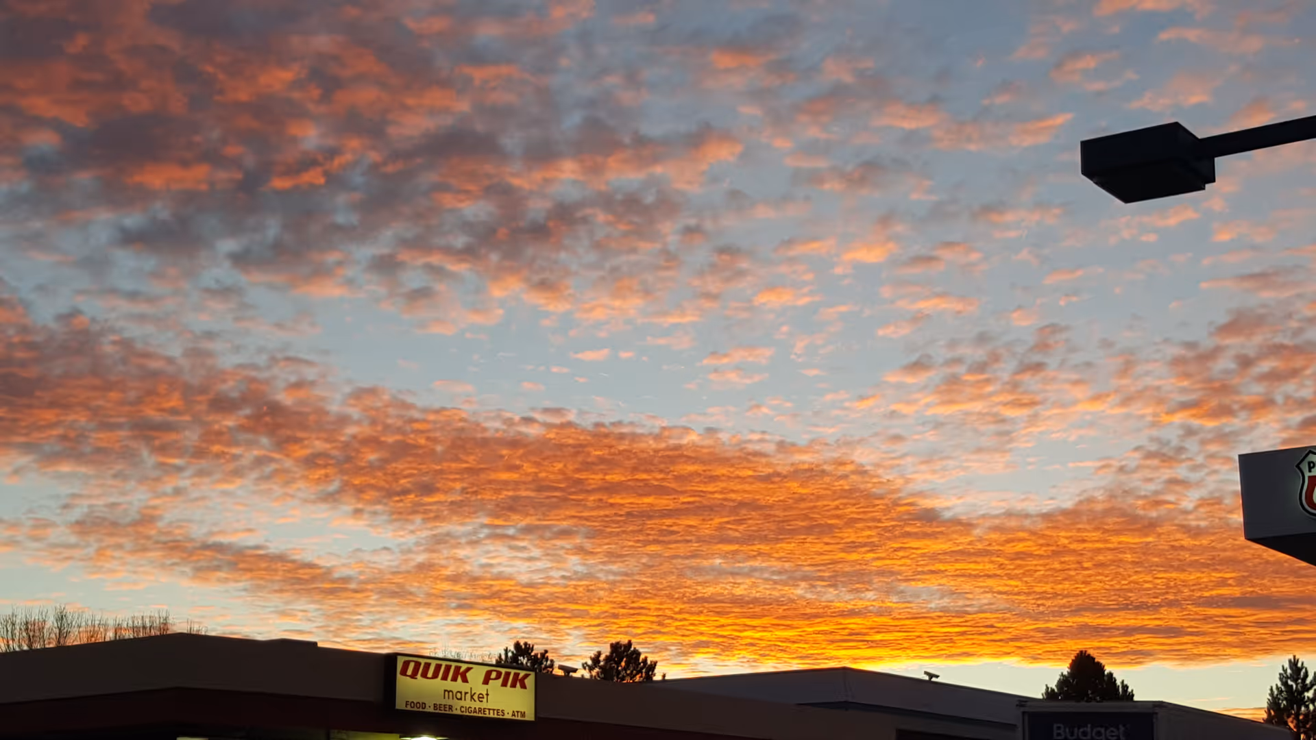 Sunset sky above a Quik Pik Market storefront and building.