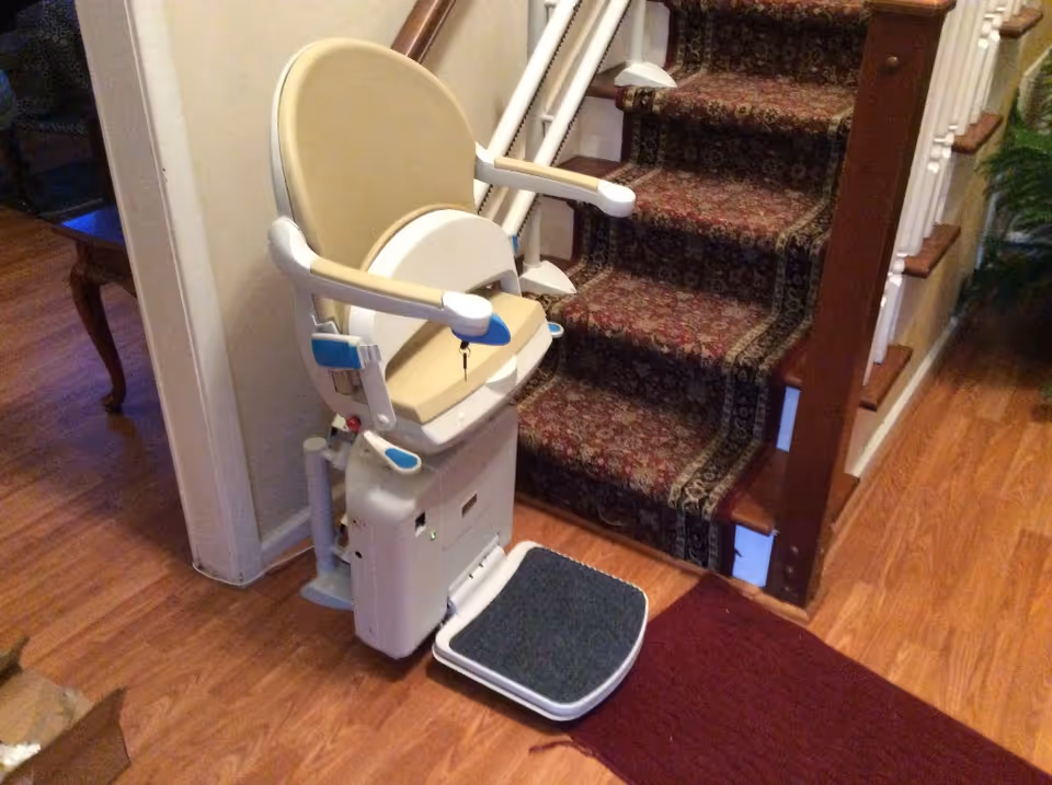 Stair lift chair beside carpeted stairs in a home interior.