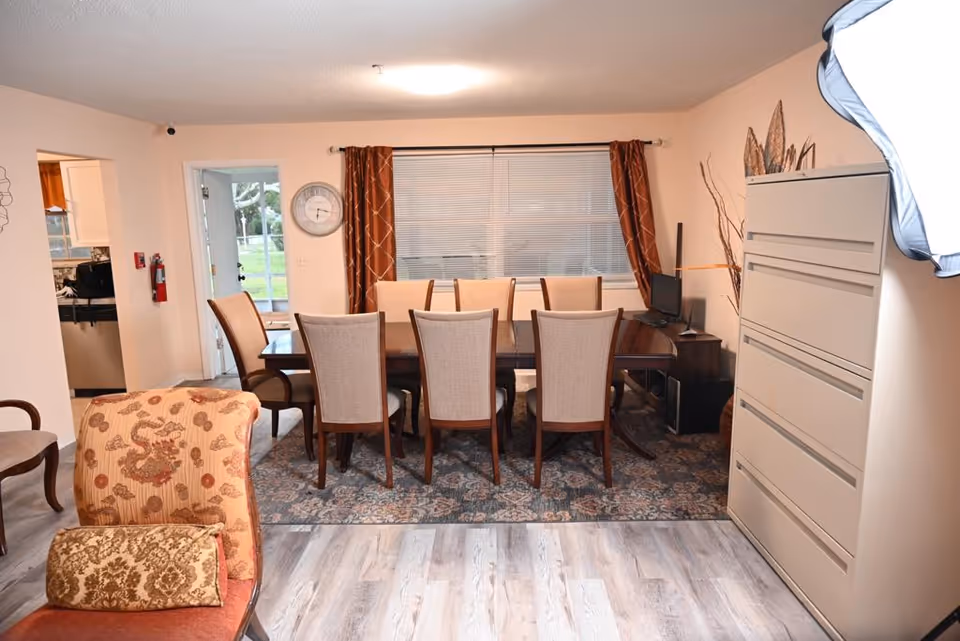 Dining room with a long table, numerous chairs, and a tall dresser along the wall.