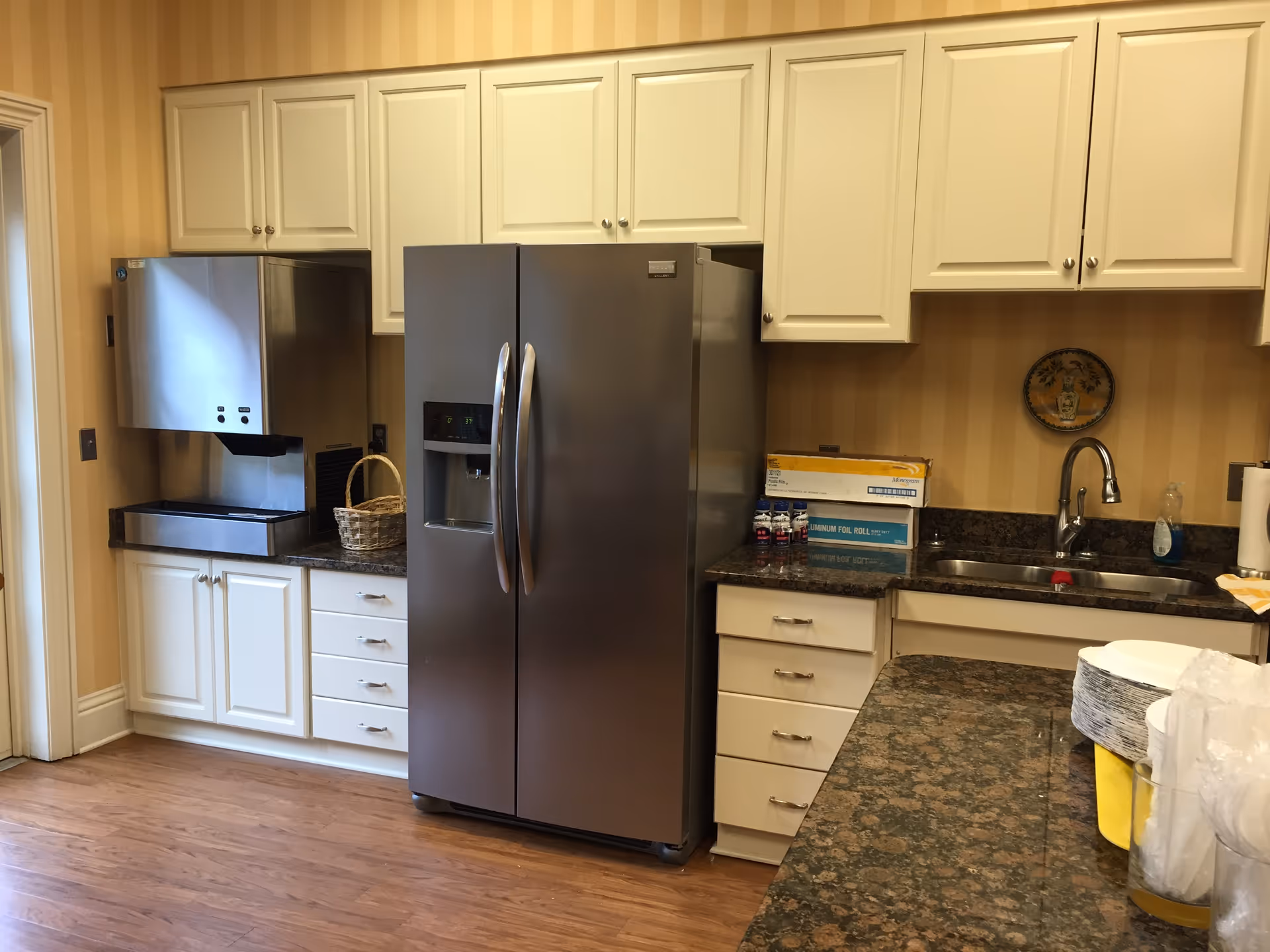Bright modern kitchen with white cabinets, stainless steel refrigerator, and granite countertops.