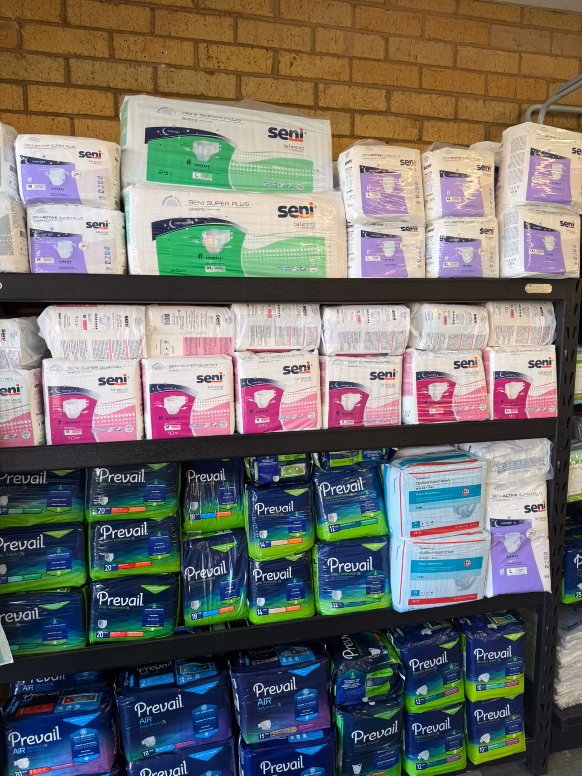 Shelves stocked with Seni and Prevail incontinence products in a facility storage area.