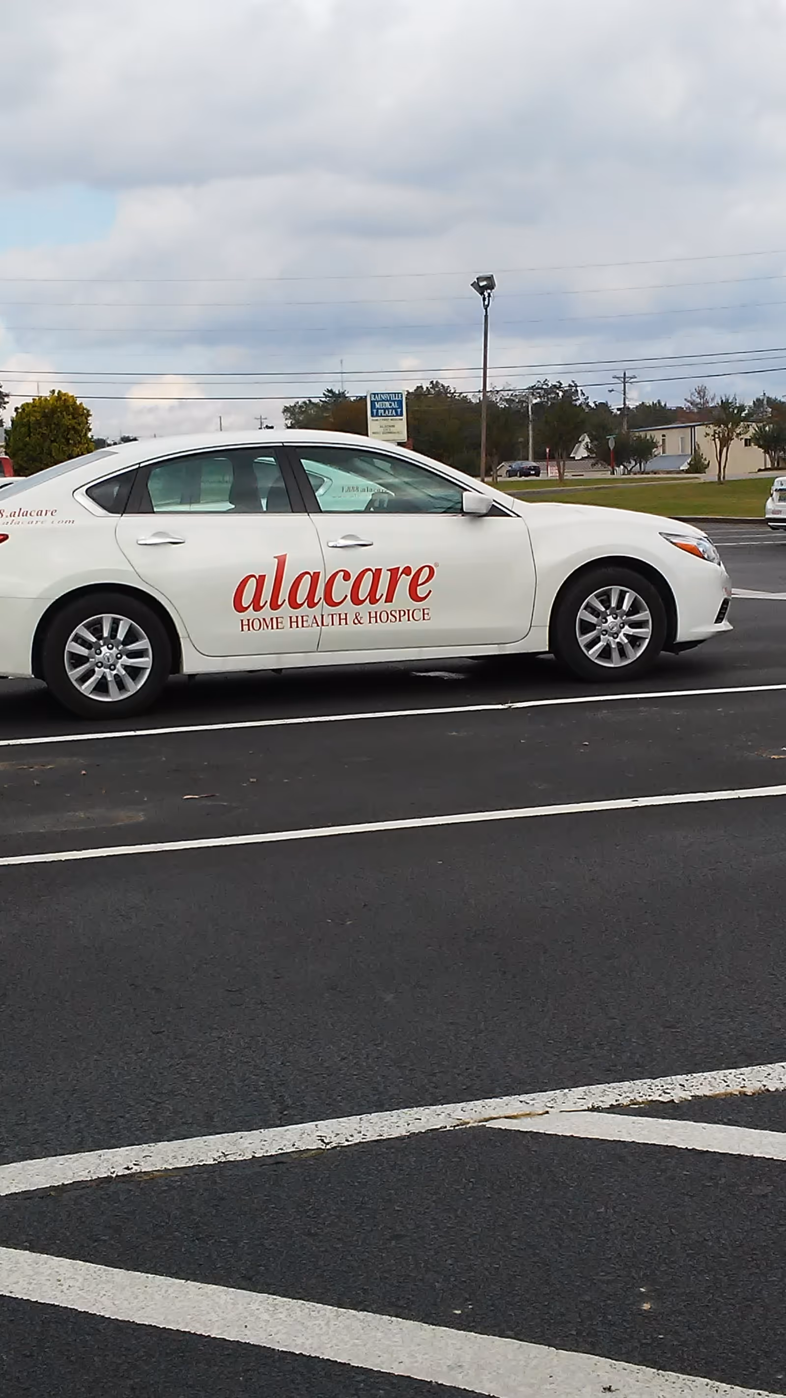 White sedan with alacare Home Health & Hospice branding parked in a lot.