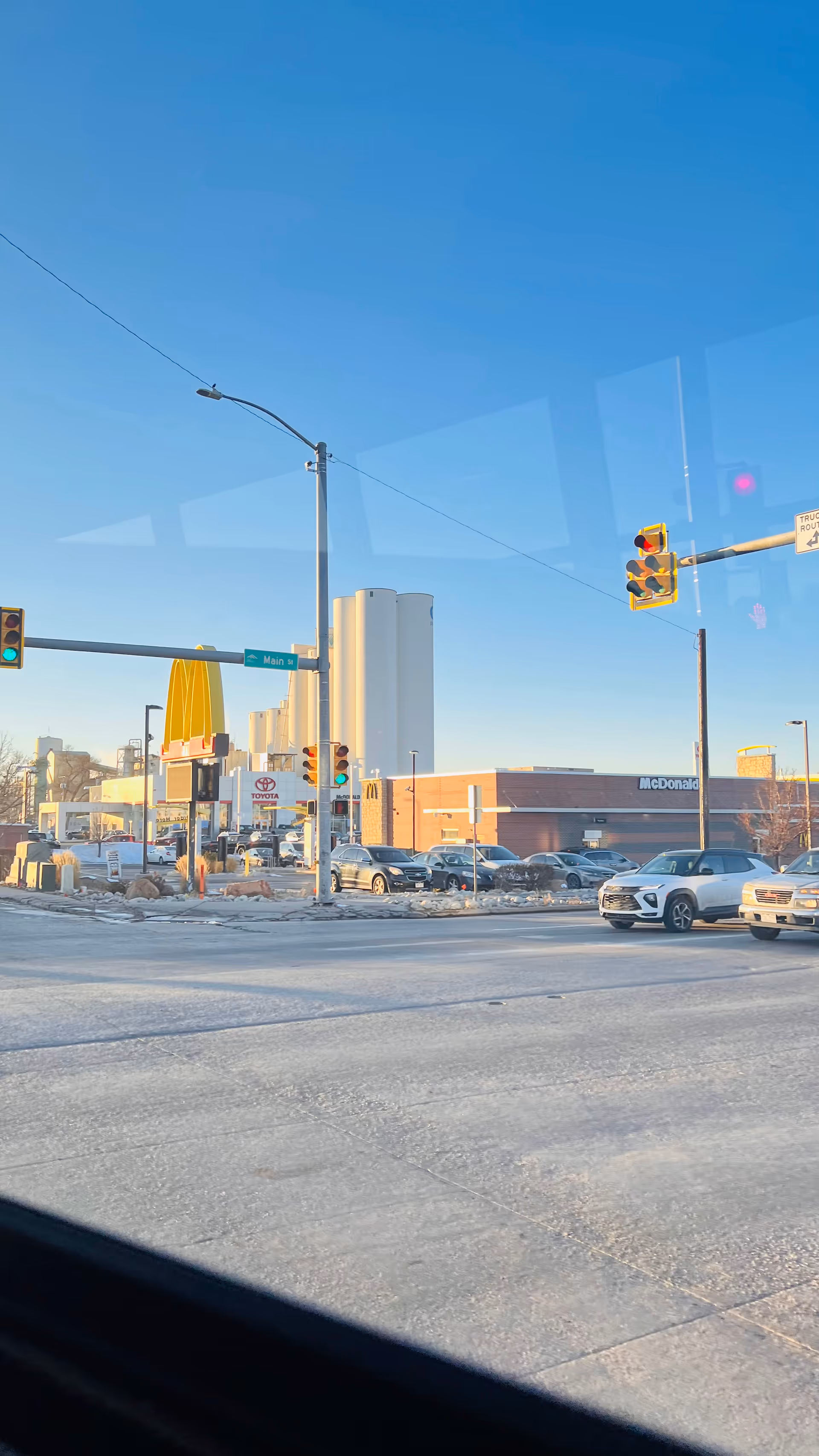 Clear blue sky over a city intersection with snow, cars, and a McDonald's in view