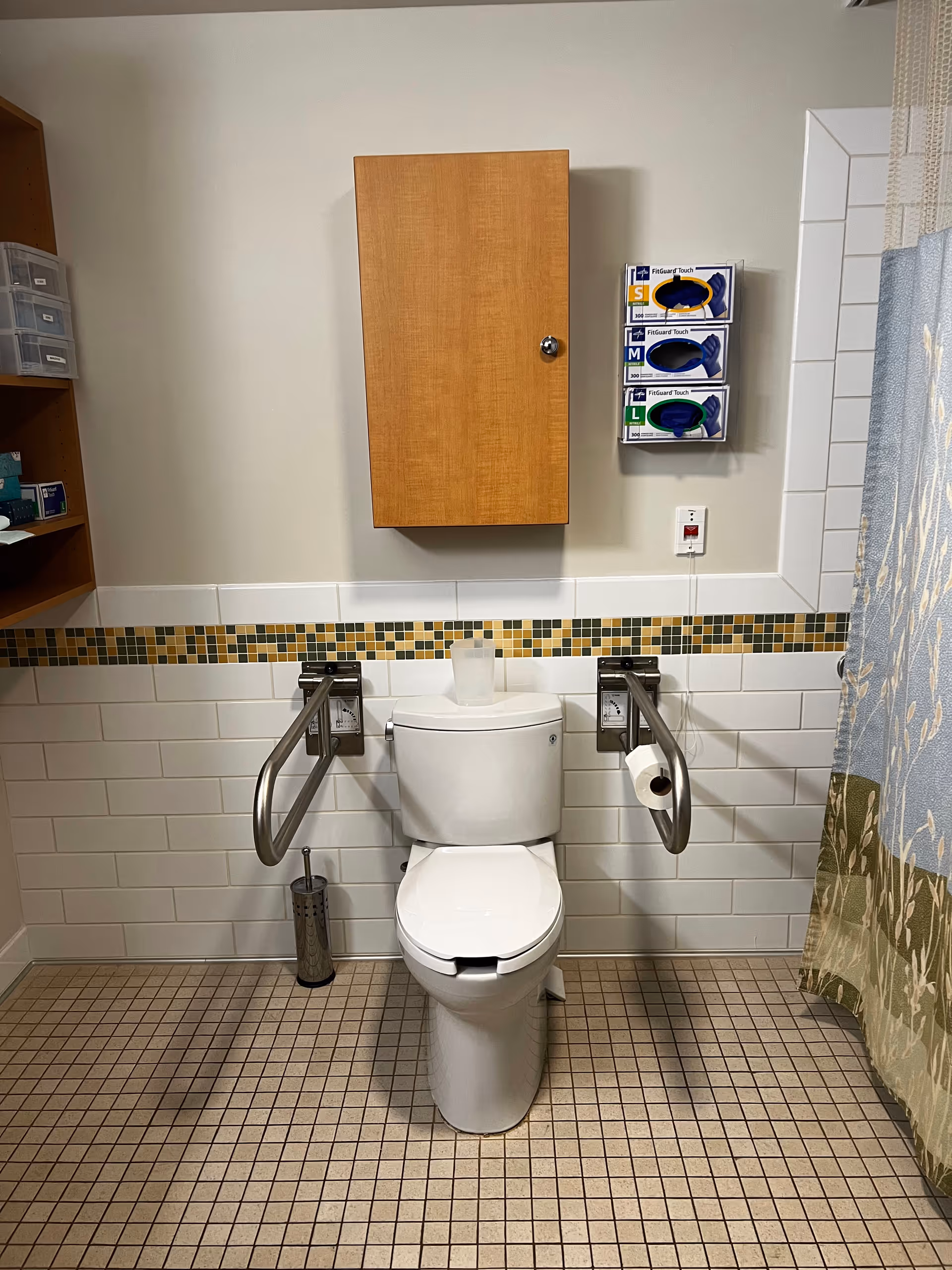 Accessible bathroom with toilet, grab bars, wall cabinet, and tiled walls.