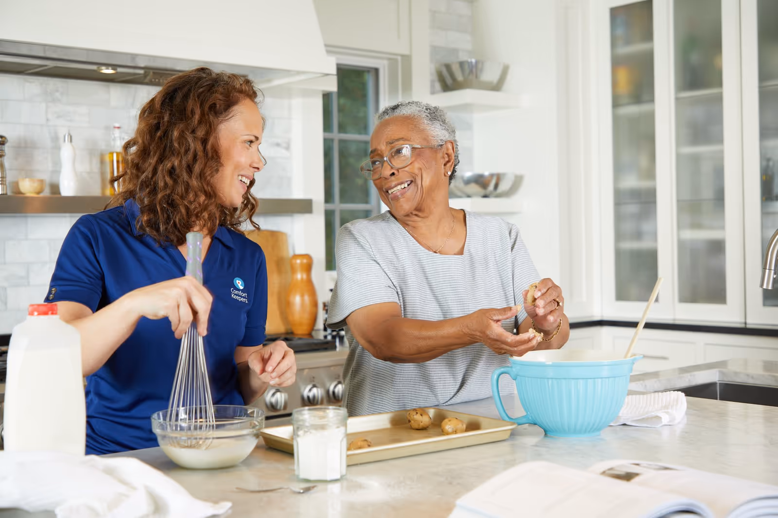 Caregiver and resident cooking together in a bright, modern kitchen.