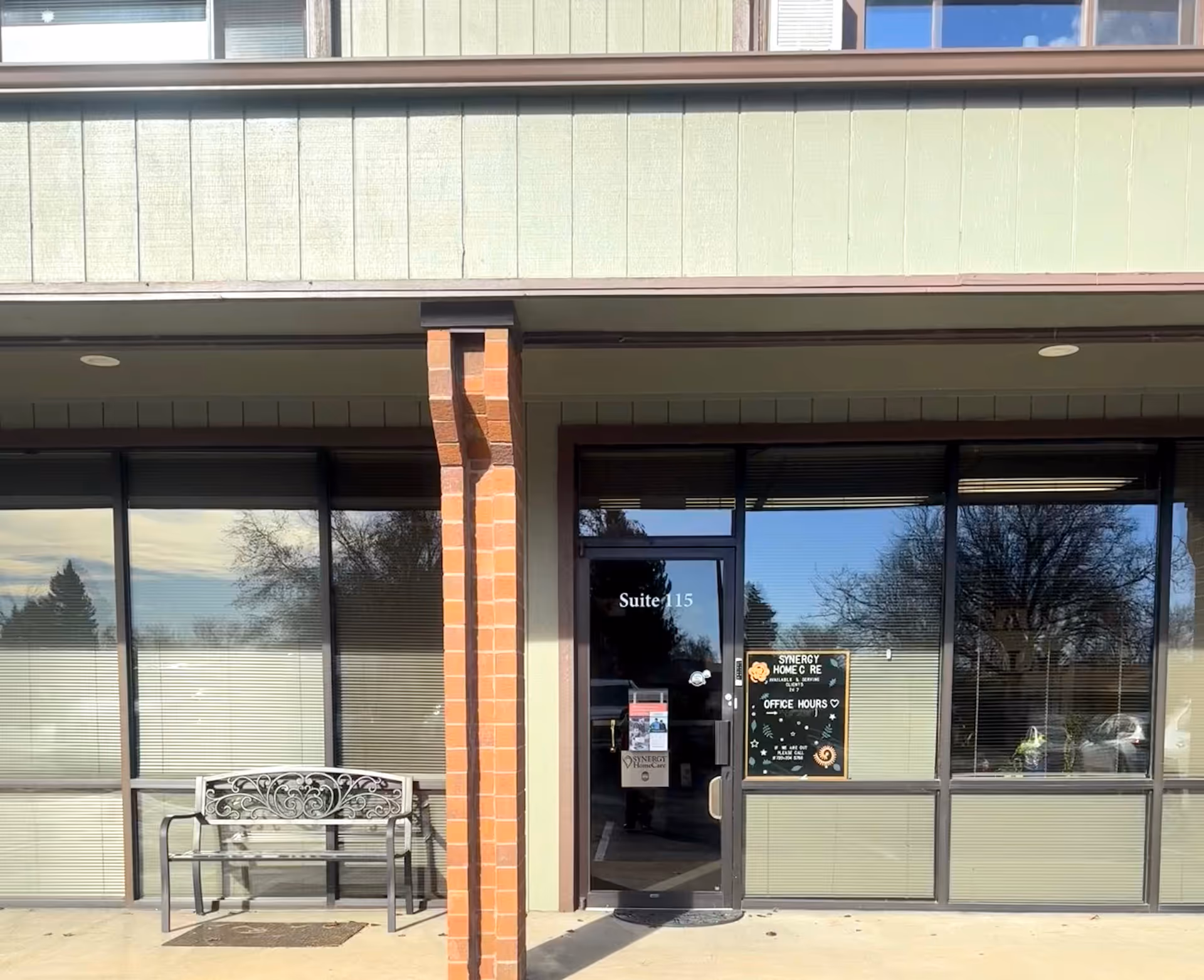 Synergy HomeCare facility exterior entrance with glass doors and a bench.