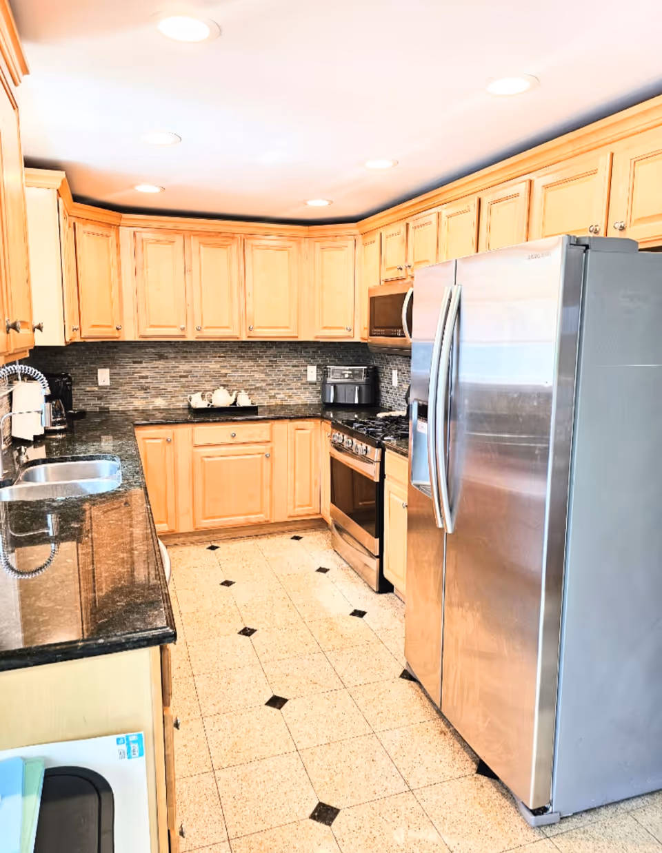 Bright kitchen with wooden cabinets, stainless appliances, and a tiled floor.
