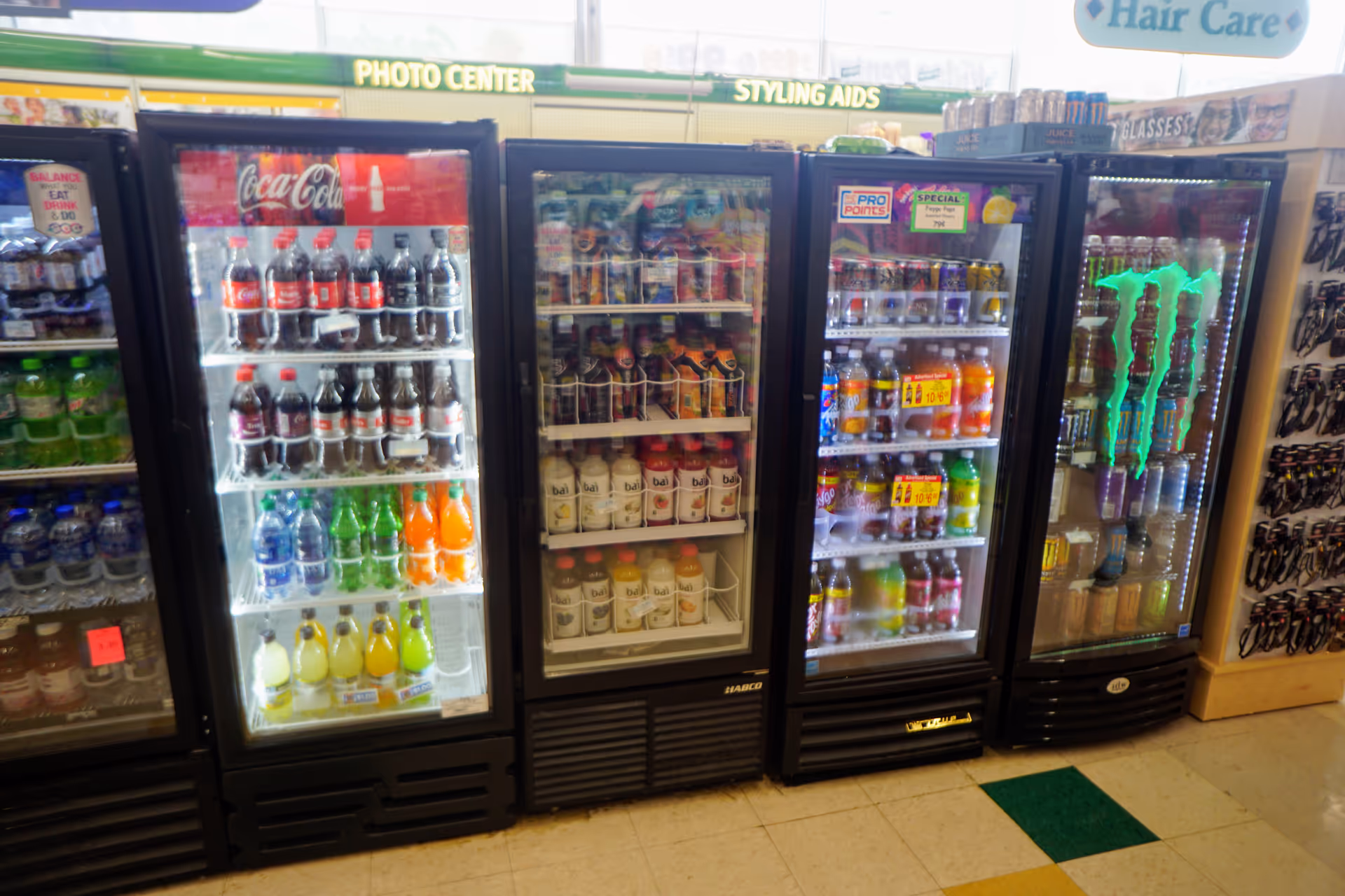Row of glass-door beverage refrigerators containing sodas, juices, and energy drinks.
