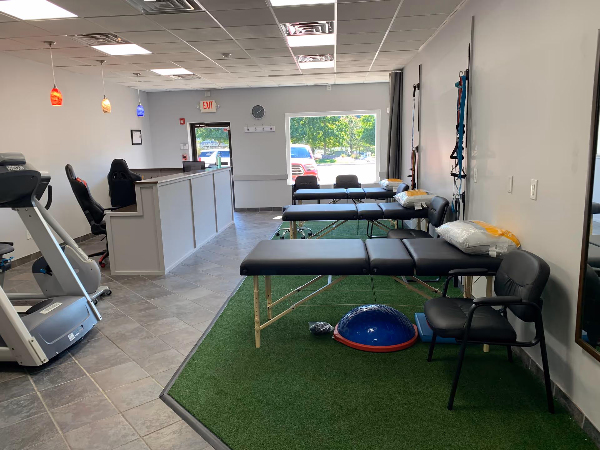 Rehabilitation therapy room with treatment tables, gym equipment, and a turf exercise area.