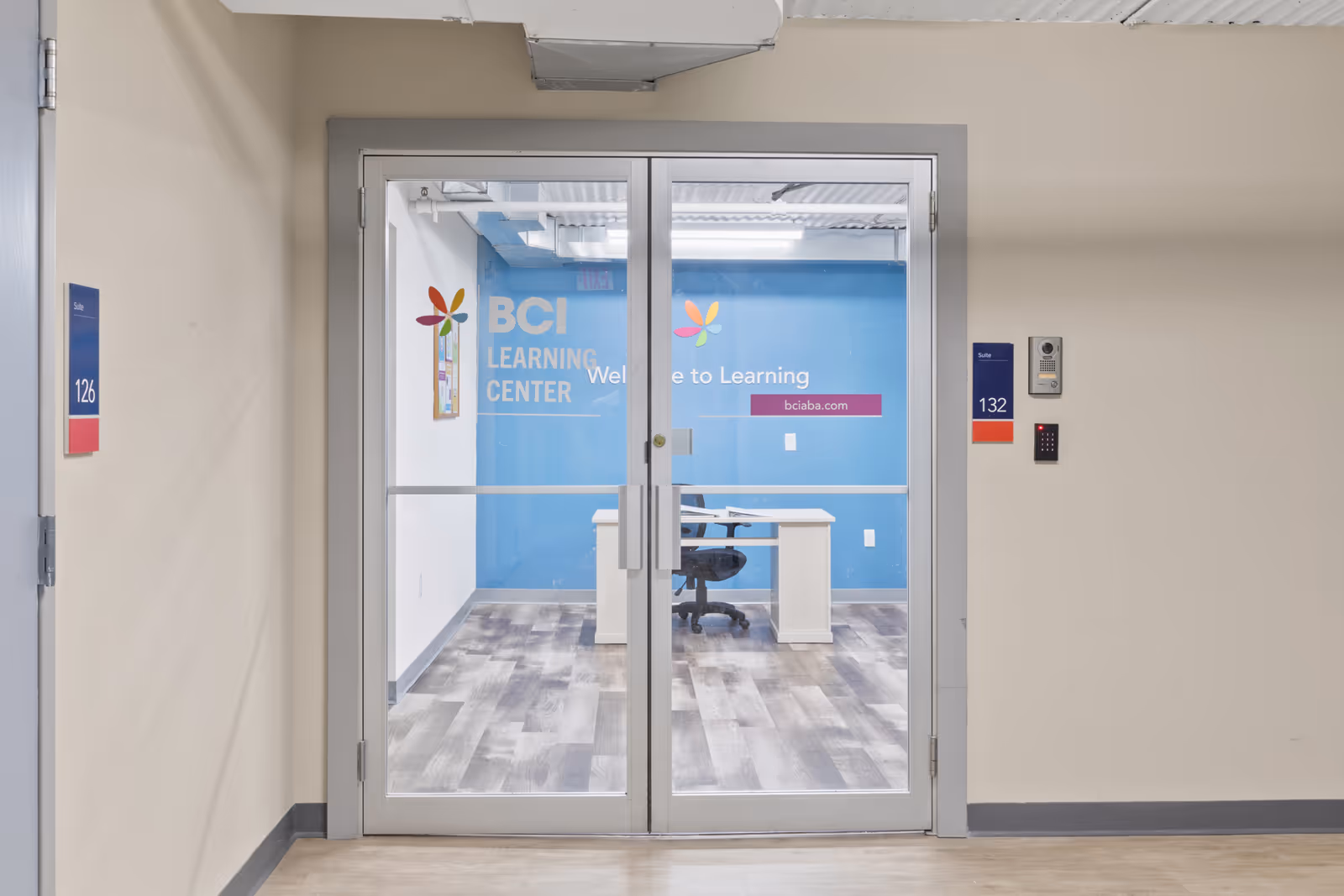 Glass double doors lead to a blue BCI Learning Center room in a beige hallway.