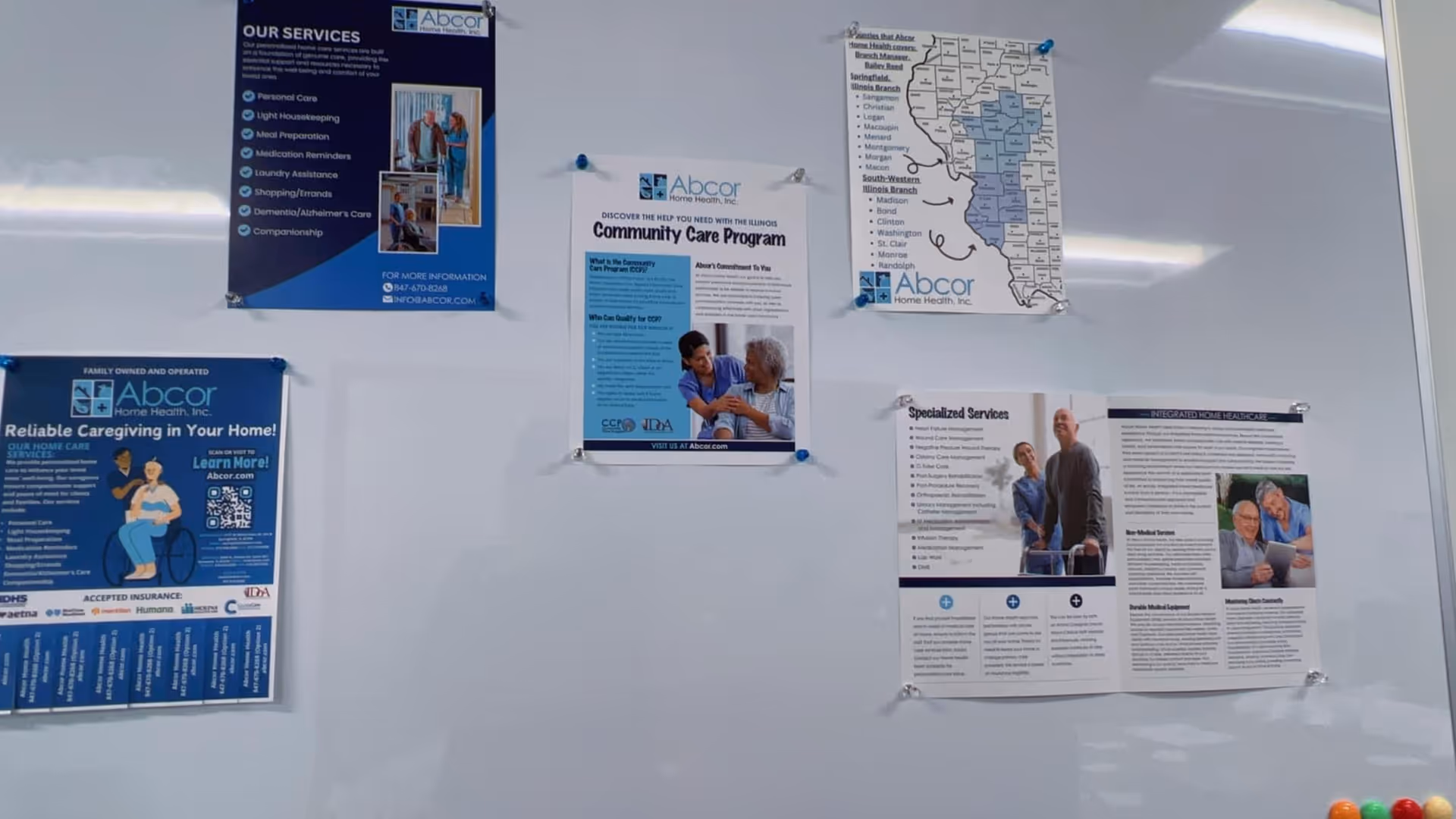 Bulletin board on a wall displaying Abcor Home Health posters and notices.