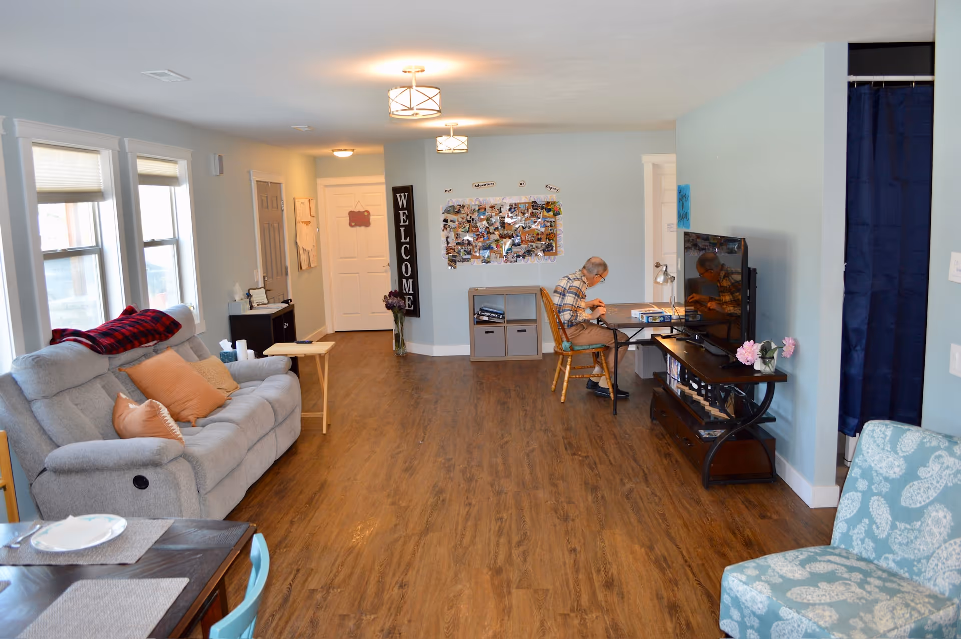 Living room of Osprey Adult Family Home with sofa, TV, and a resident.