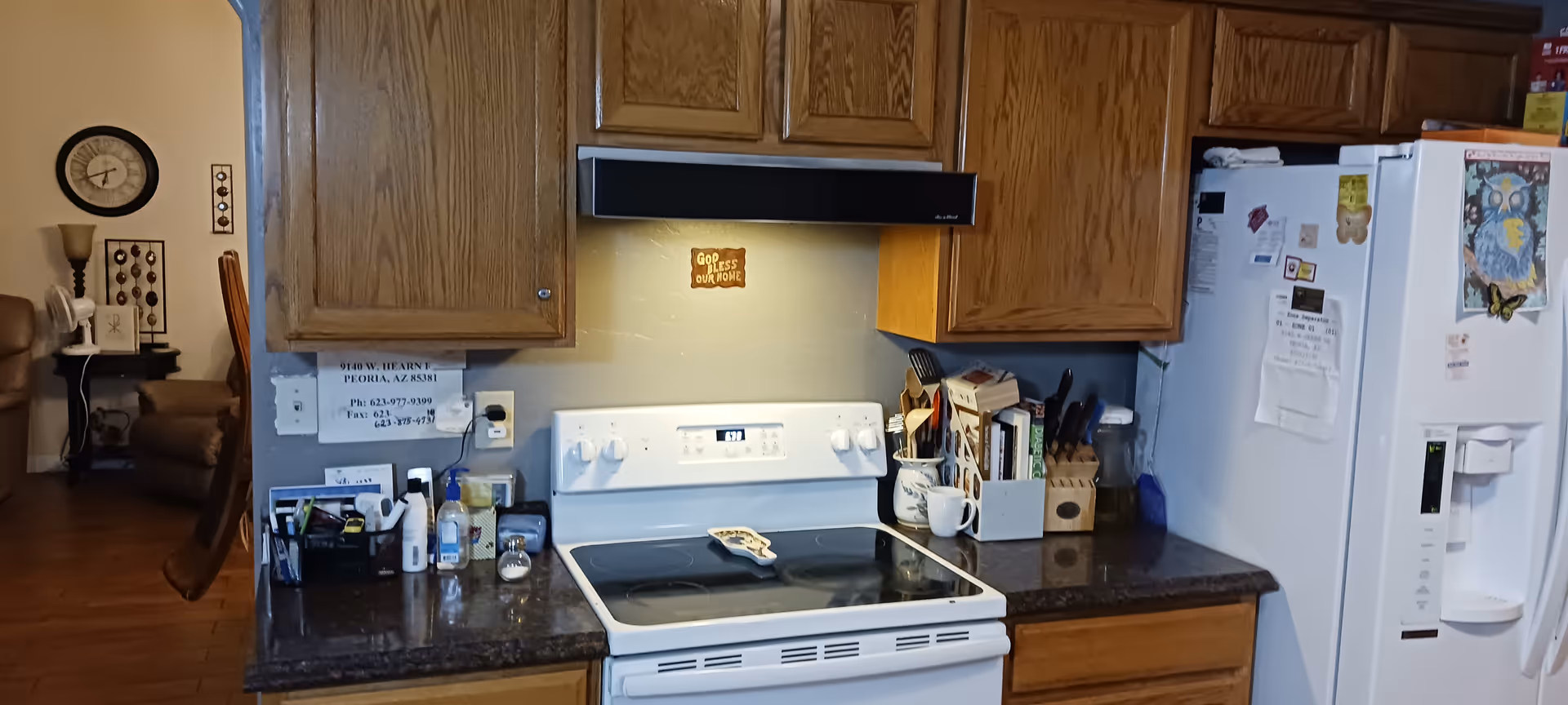 A home-style kitchen in a senior living facility with wooden cabinets, white stove, and refrigerator.