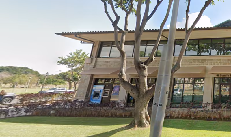 Exterior view of a Senior Helpers building with trees, windows, and a landscaped walkway.