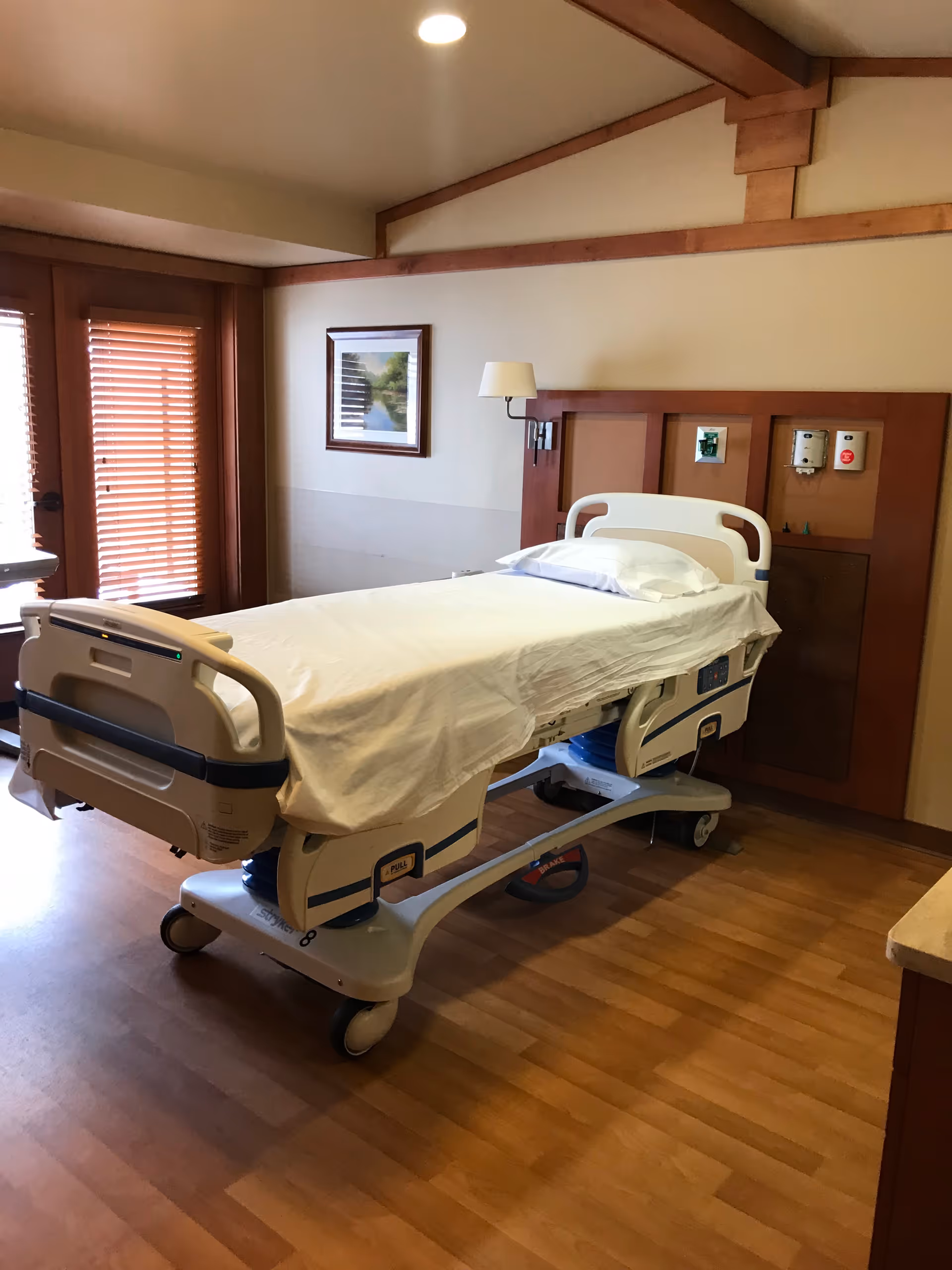 Hospital-style patient room with an adjustable bed and wall-mounted medical equipment.