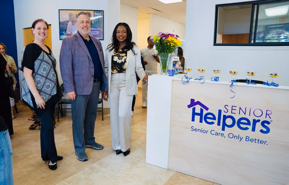 Group of people at a Senior Helpers reception desk in a bright lobby.