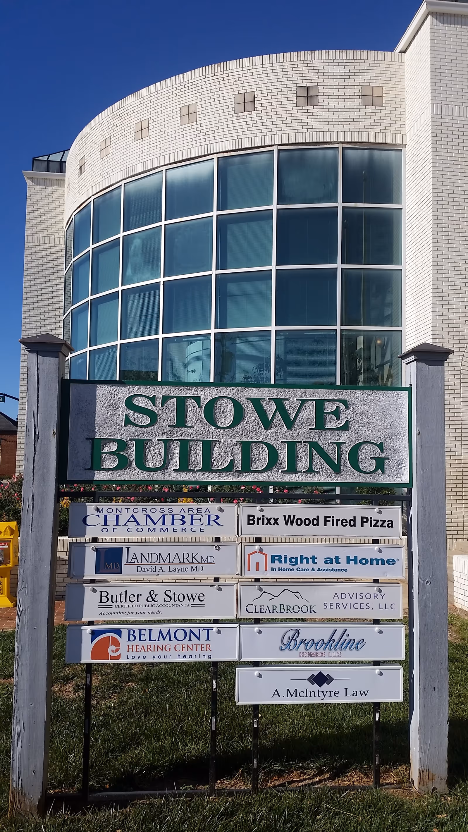 Curved glass front building with multiple signs, including Right at Home and Stowe Building.